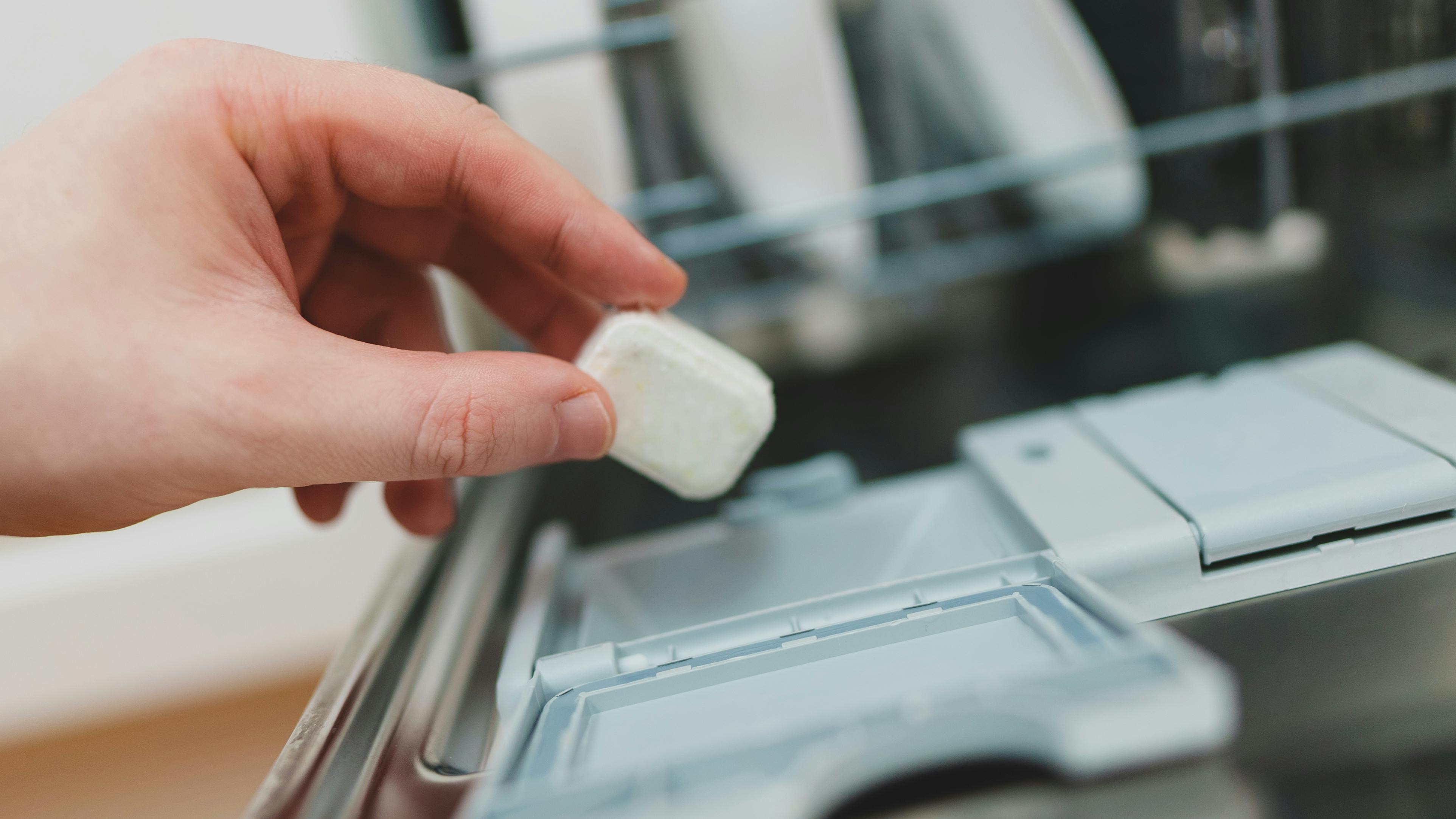 Hånd putter opvasketab i opvaskemaskine