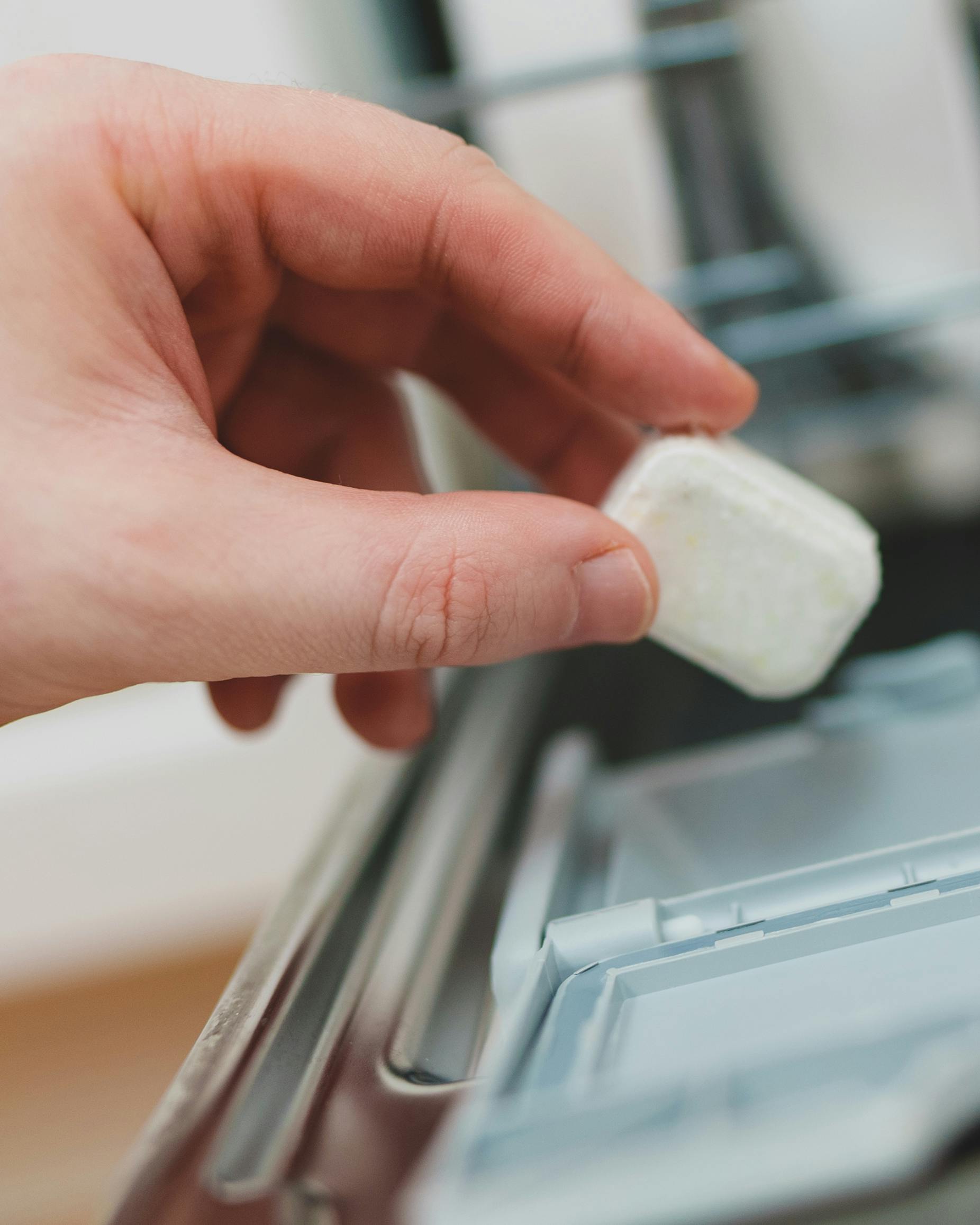 Hånd putter opvasketab i opvaskemaskine