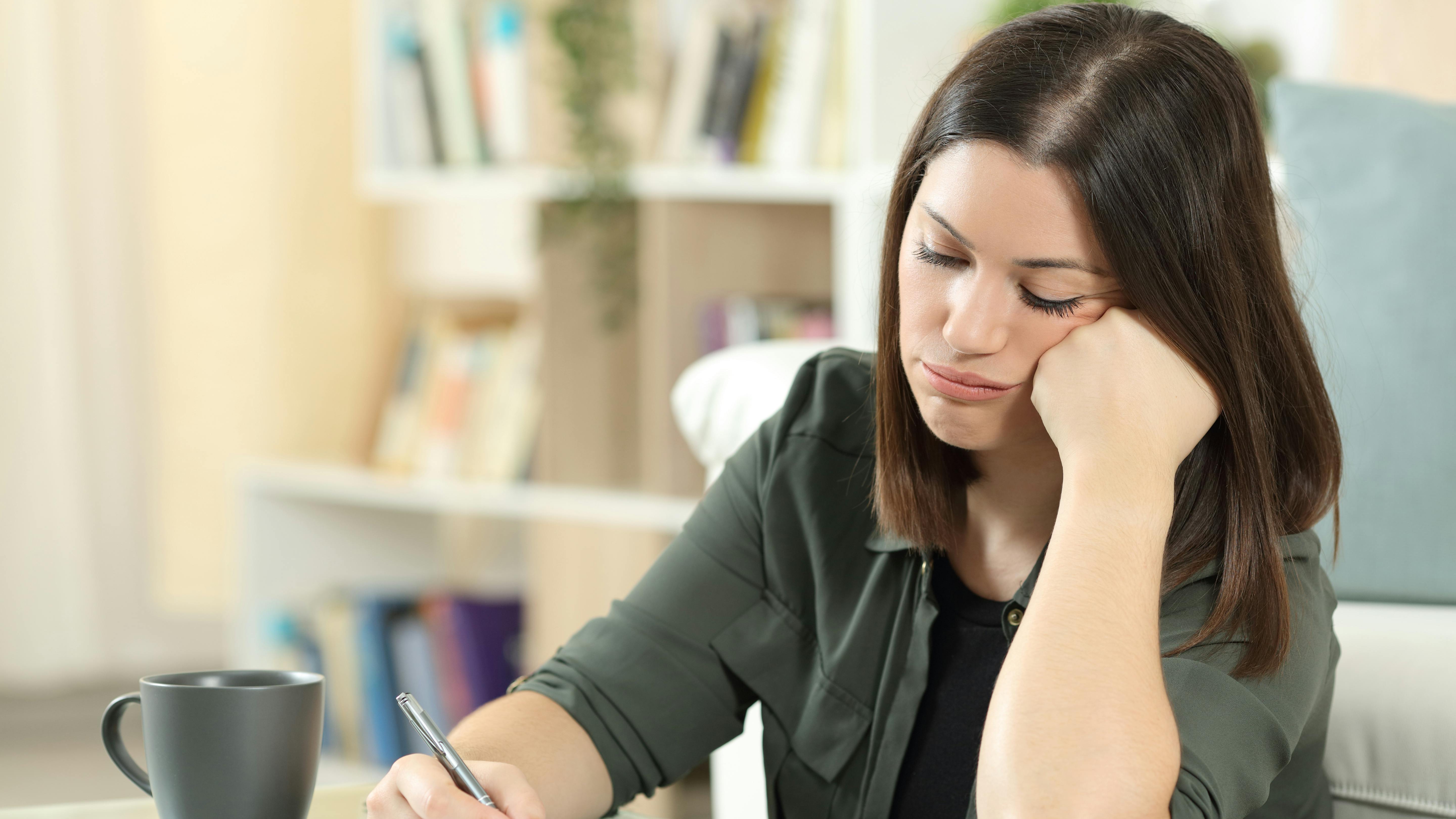 Frustreret eller koncentreret kvinder sidder med blok og pen