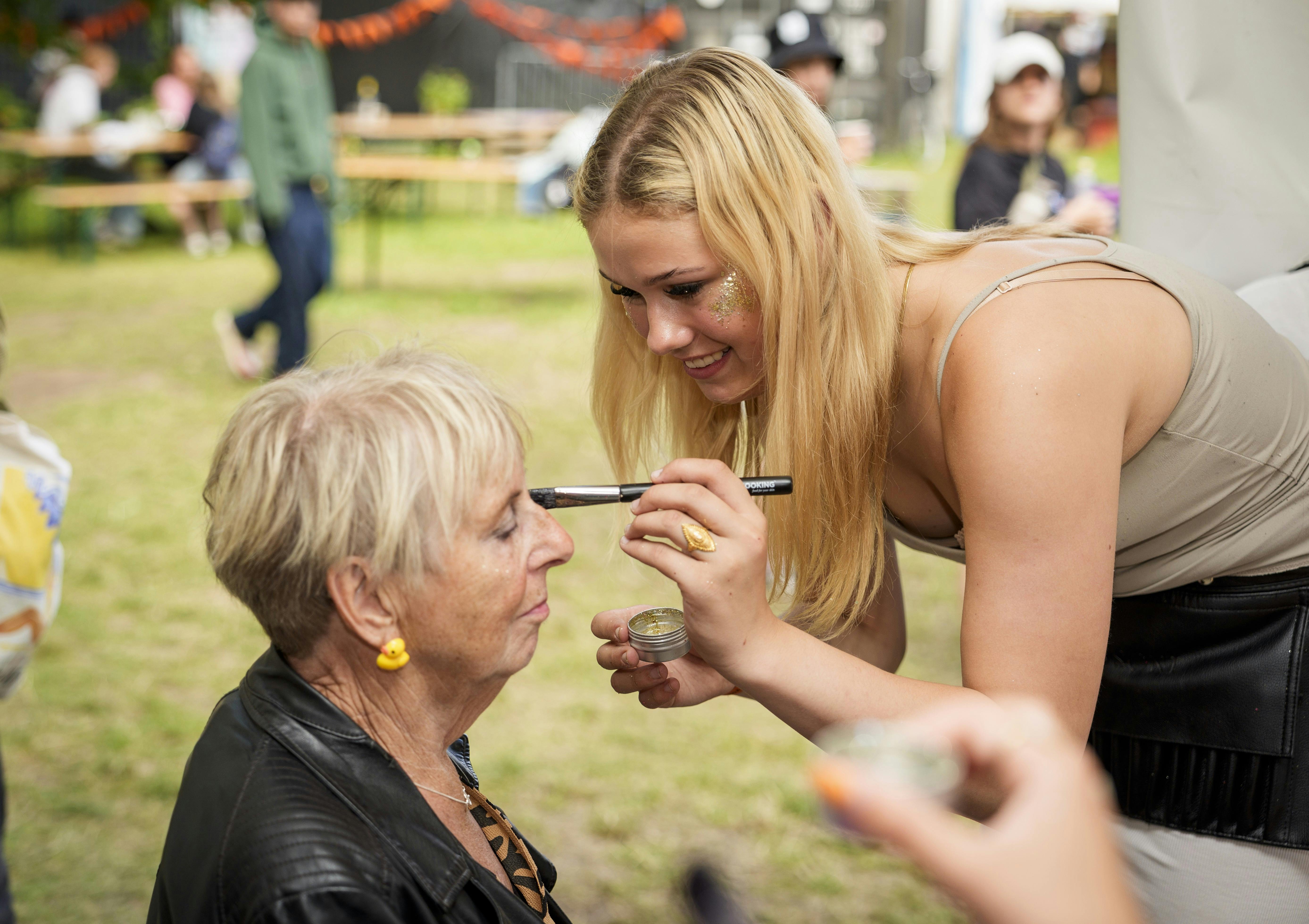 Glitter på kindbenene skal der til, og Frida, som også er frivillig på festivalen, sørger for, at Bodil bliver pyntet.