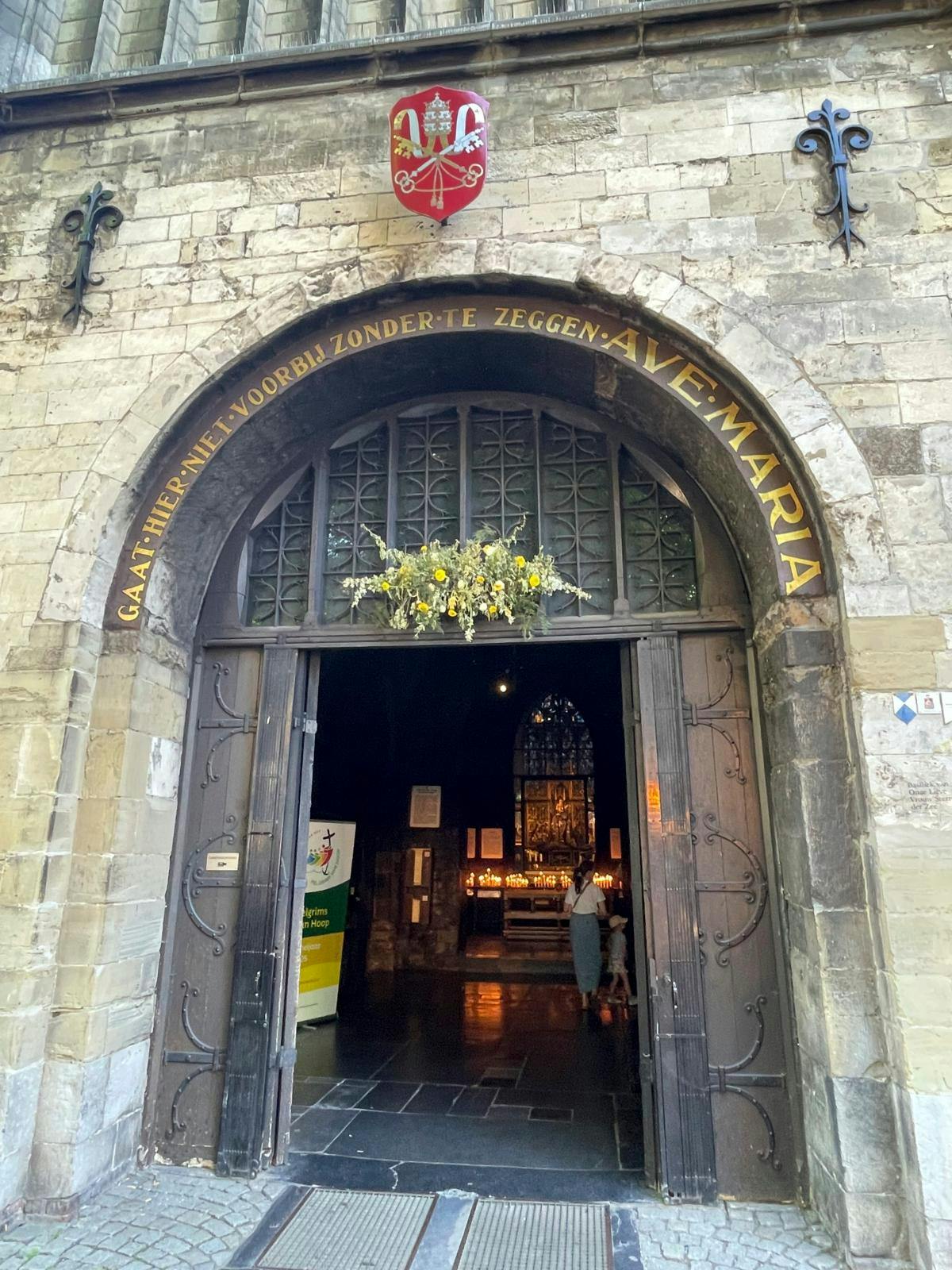 Indgang til en gammel kirke, hvor der er tændt masser af stearinlys.