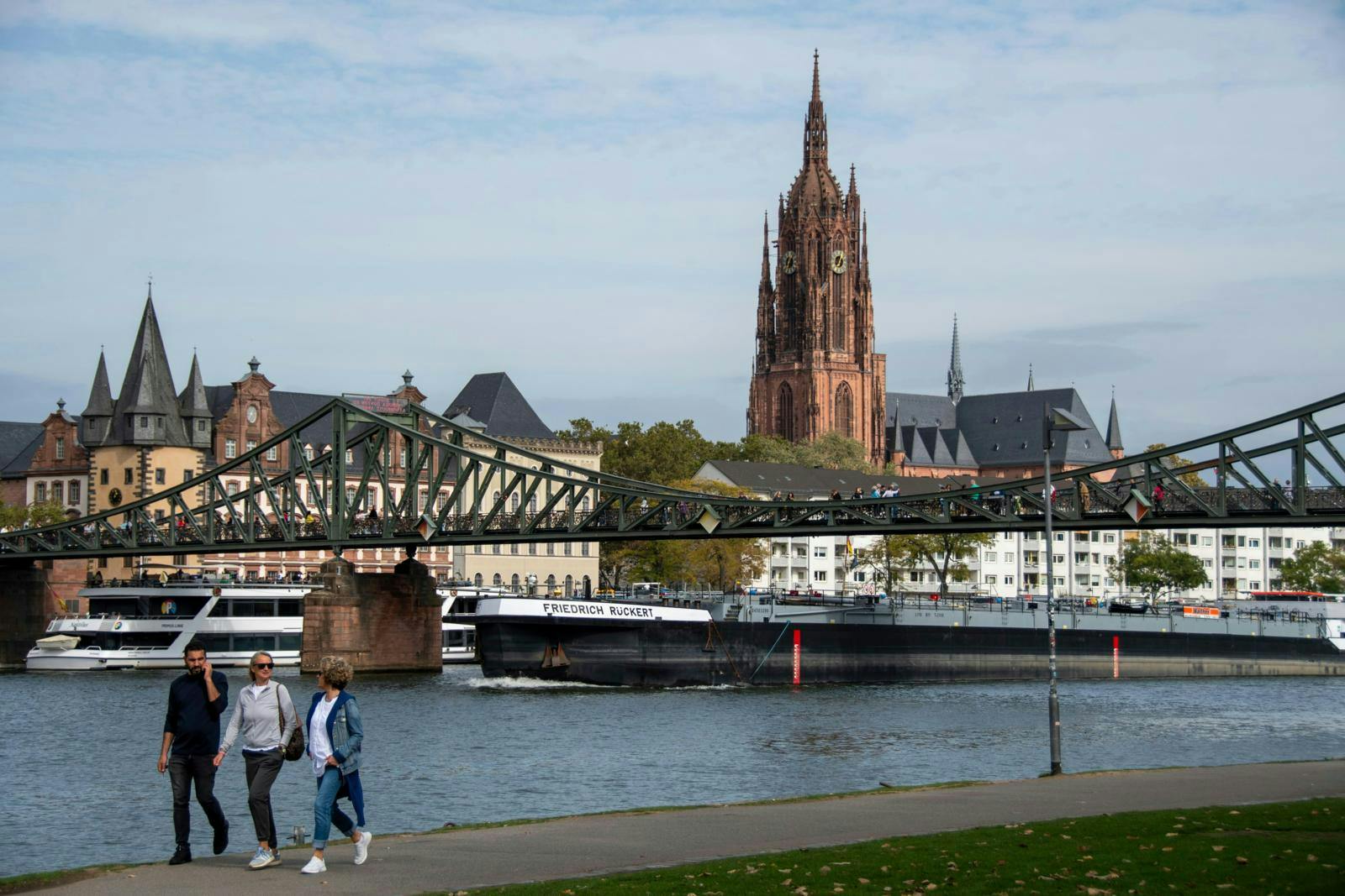 Mennesker ved kajen i Maastricht med en kirke i baggrunden.