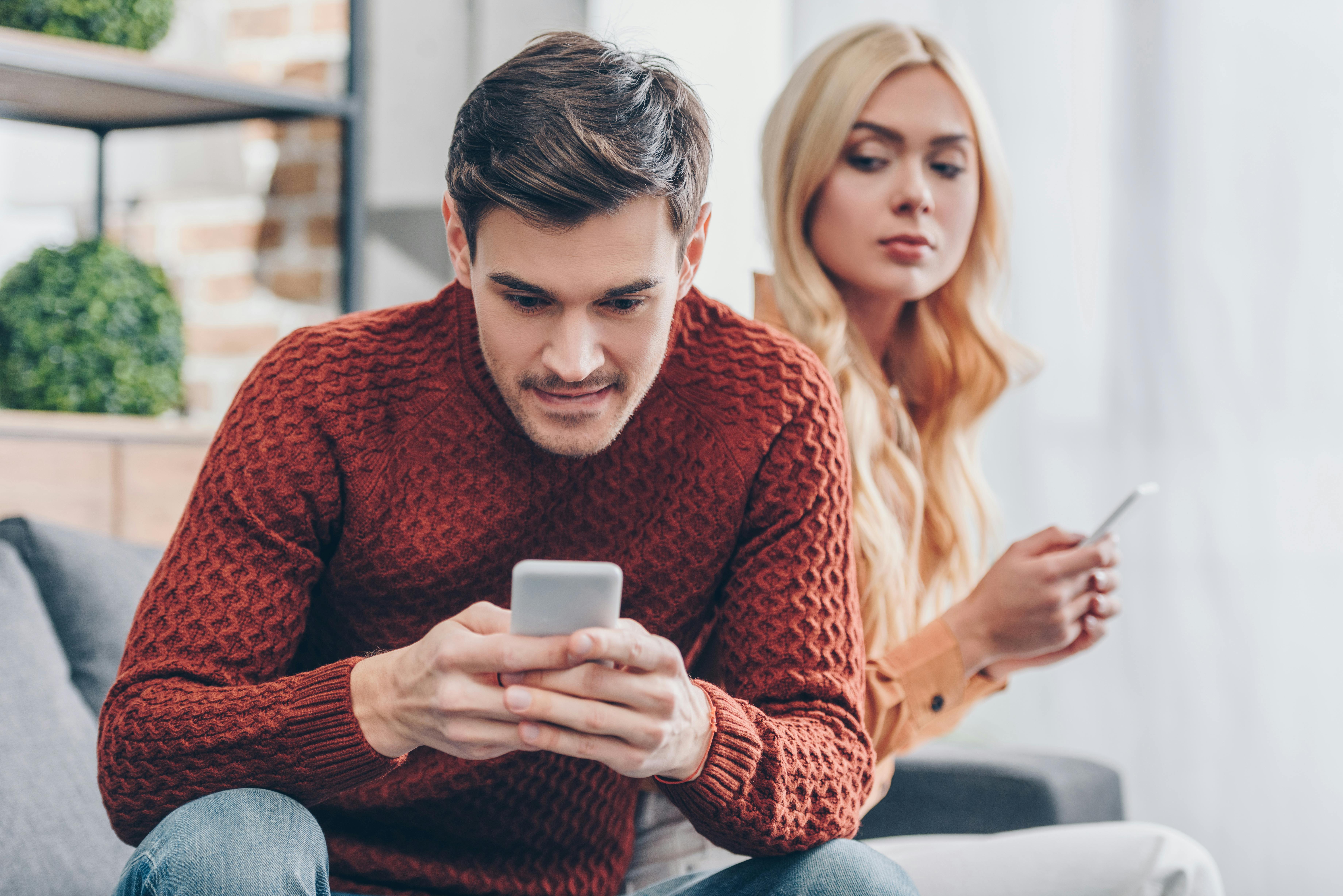 Kvinde kigger på mand med telefon