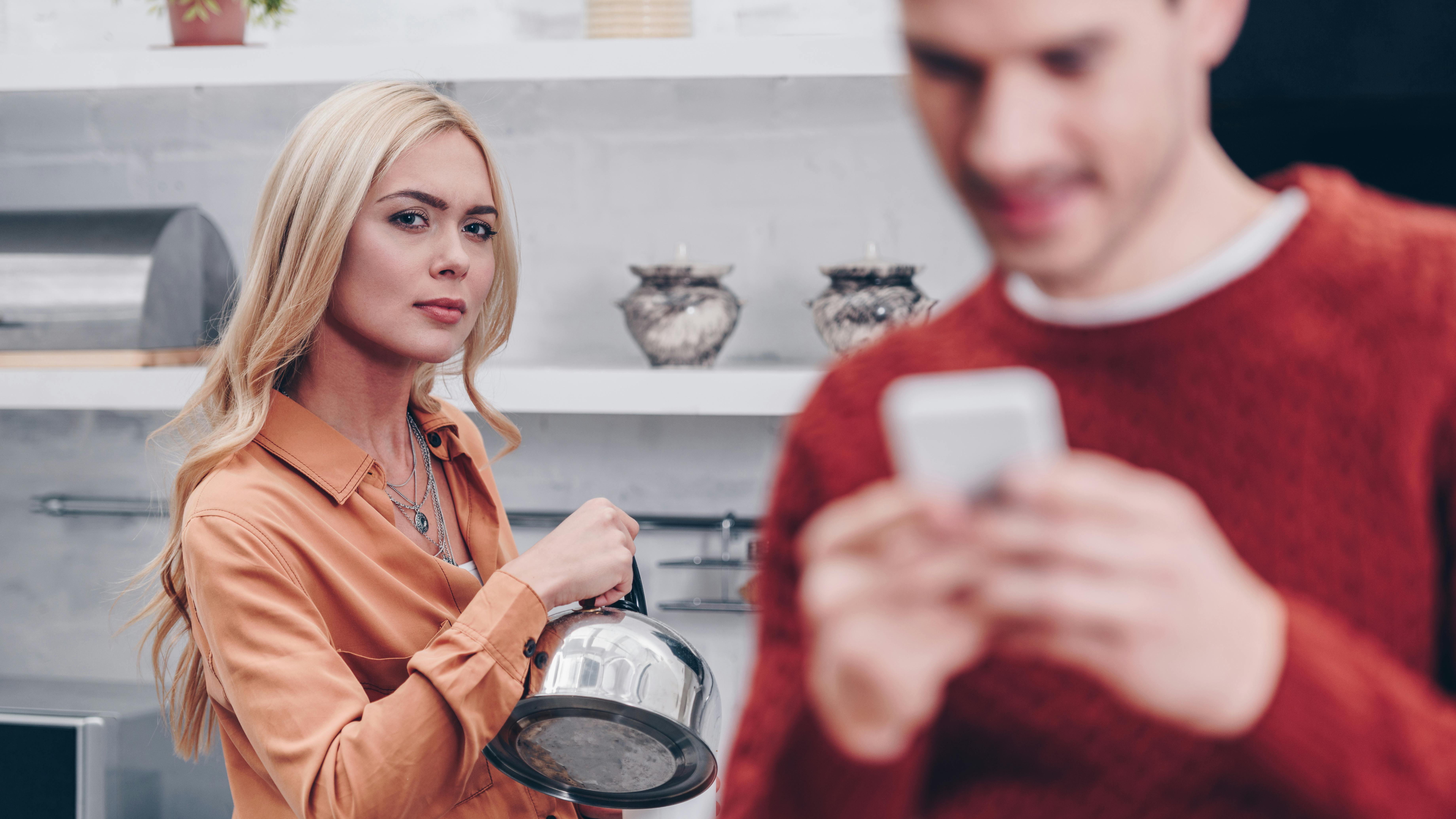 Kvinde kigger vredt på mand med telefon