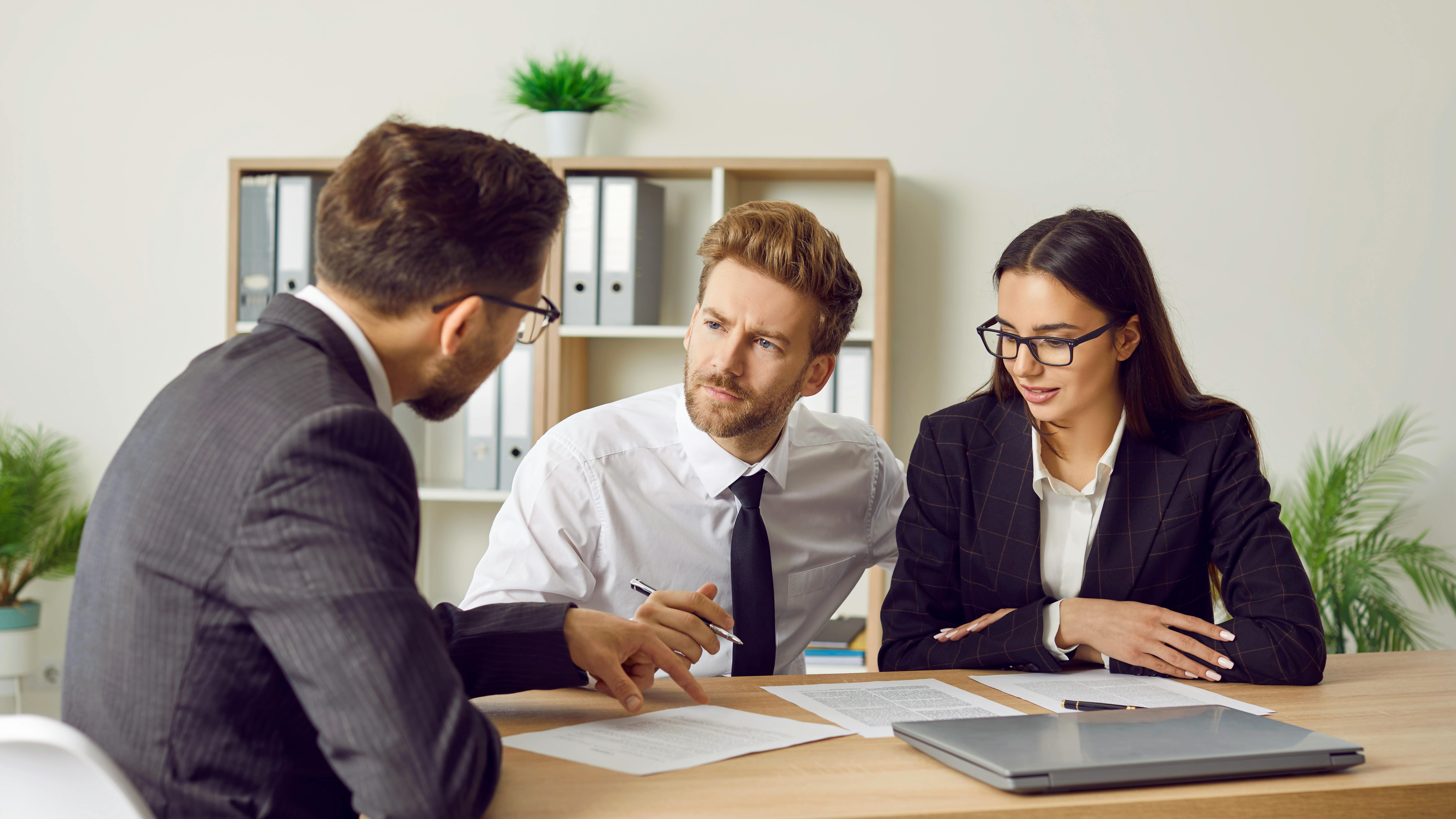 To mænd og kvinde ved skrivebord