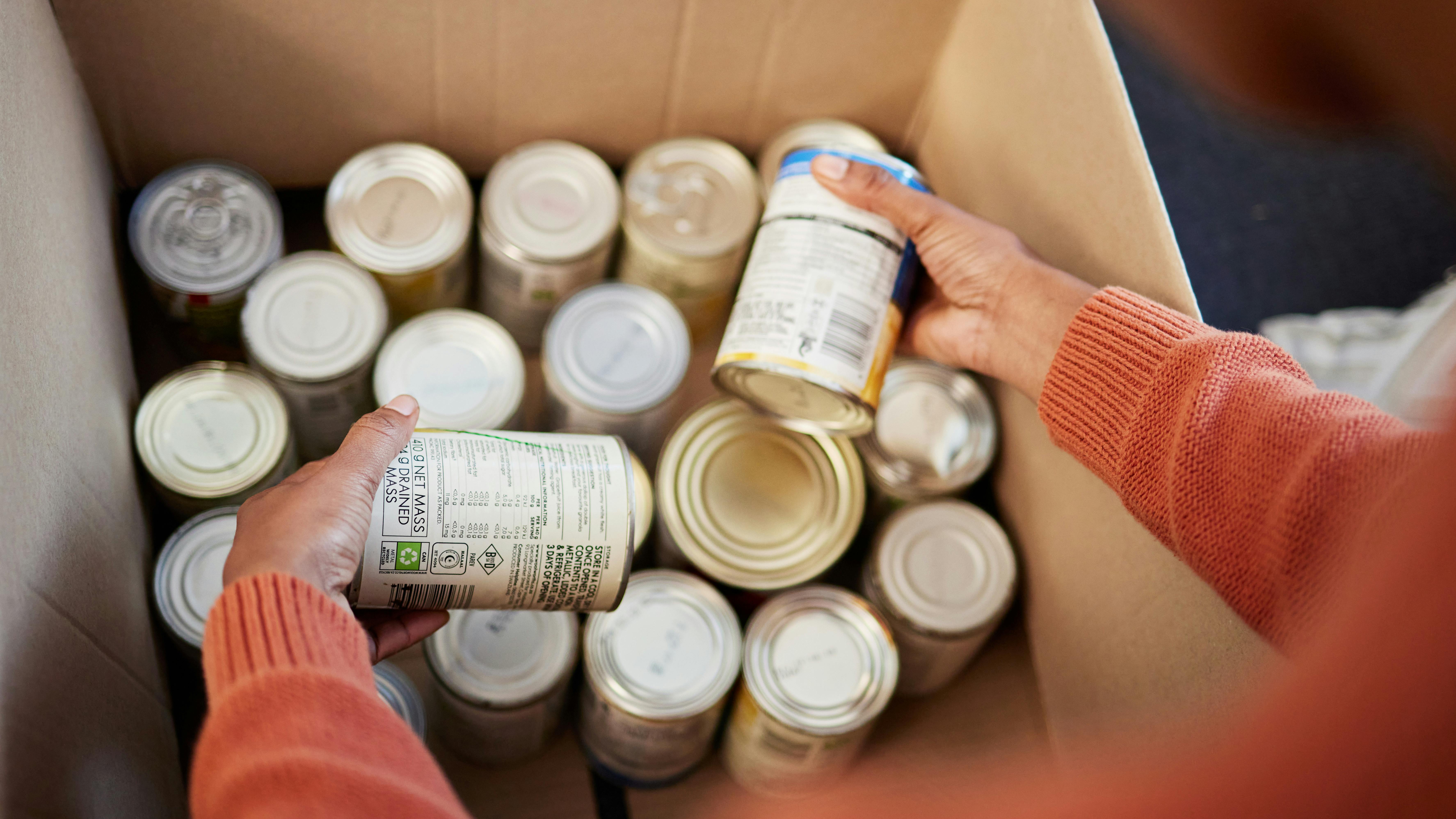 Kasse med dåsemad og to hænder