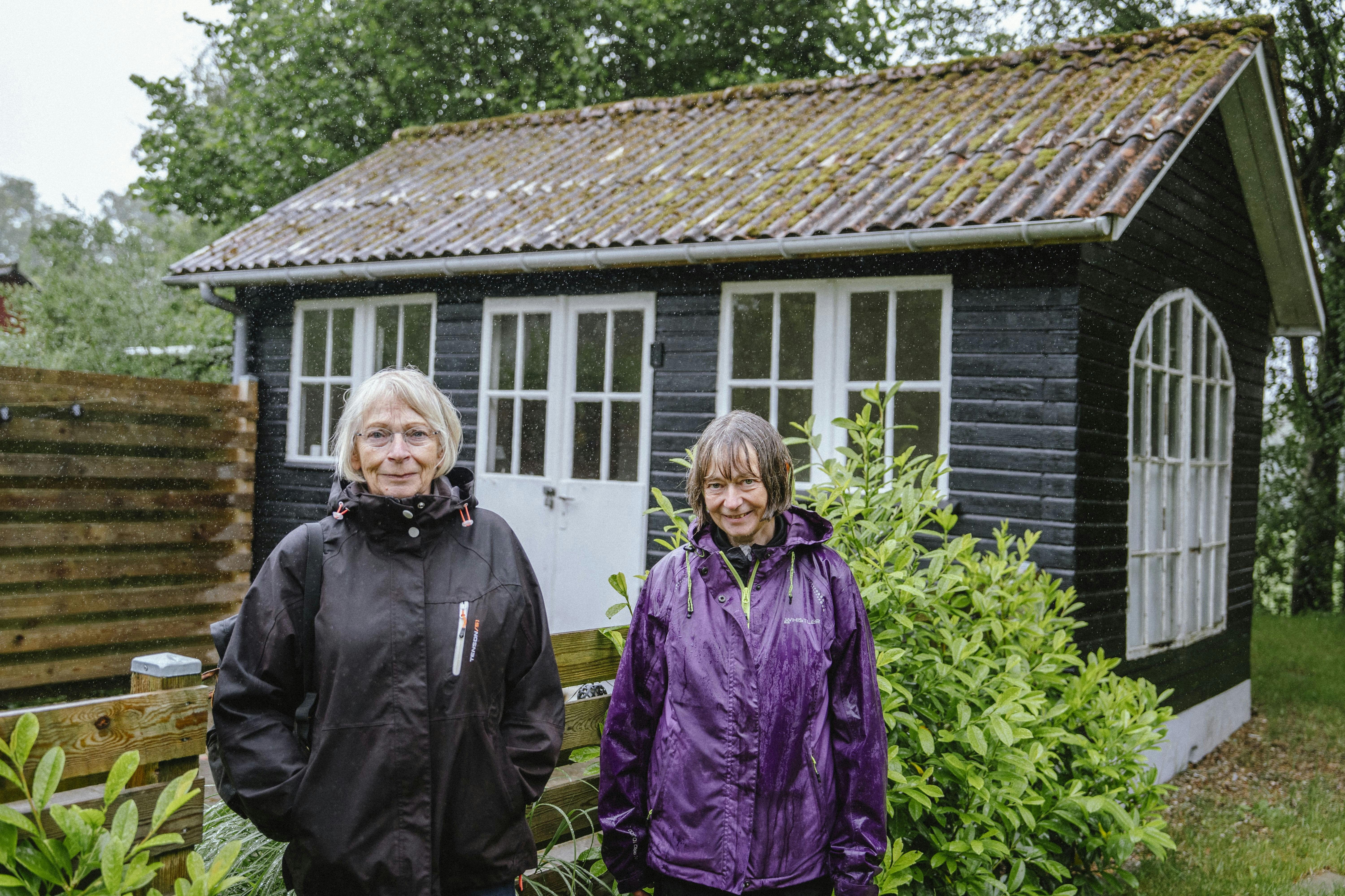 Søstrene Birgit Støchkel og Karen Margrethe Lauridsen, som de ser ud i dag, foran barndommens kolonihavehus i Hjelmhaverne.