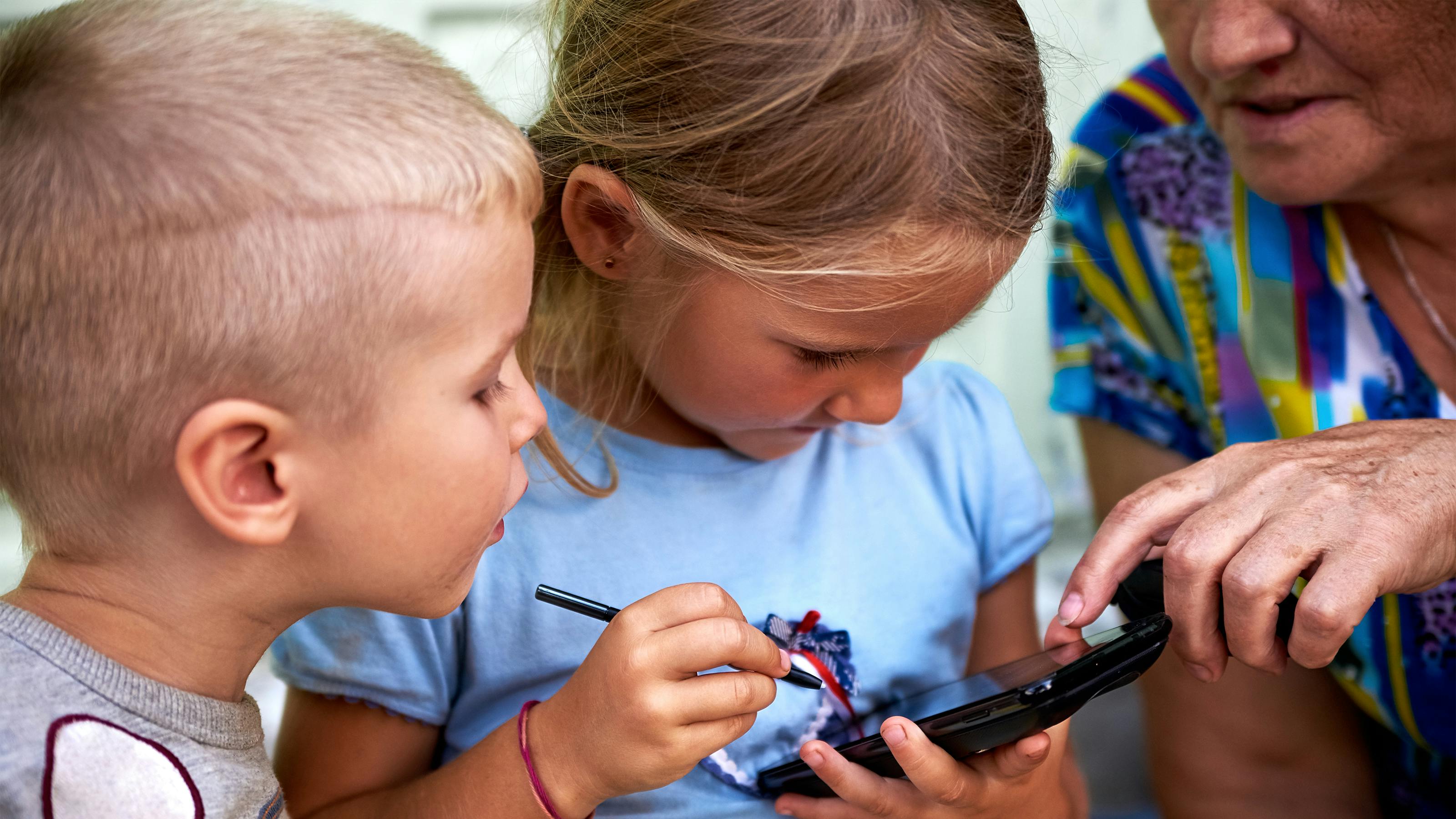 Dreng og pige kigger på mobil med bedstemor