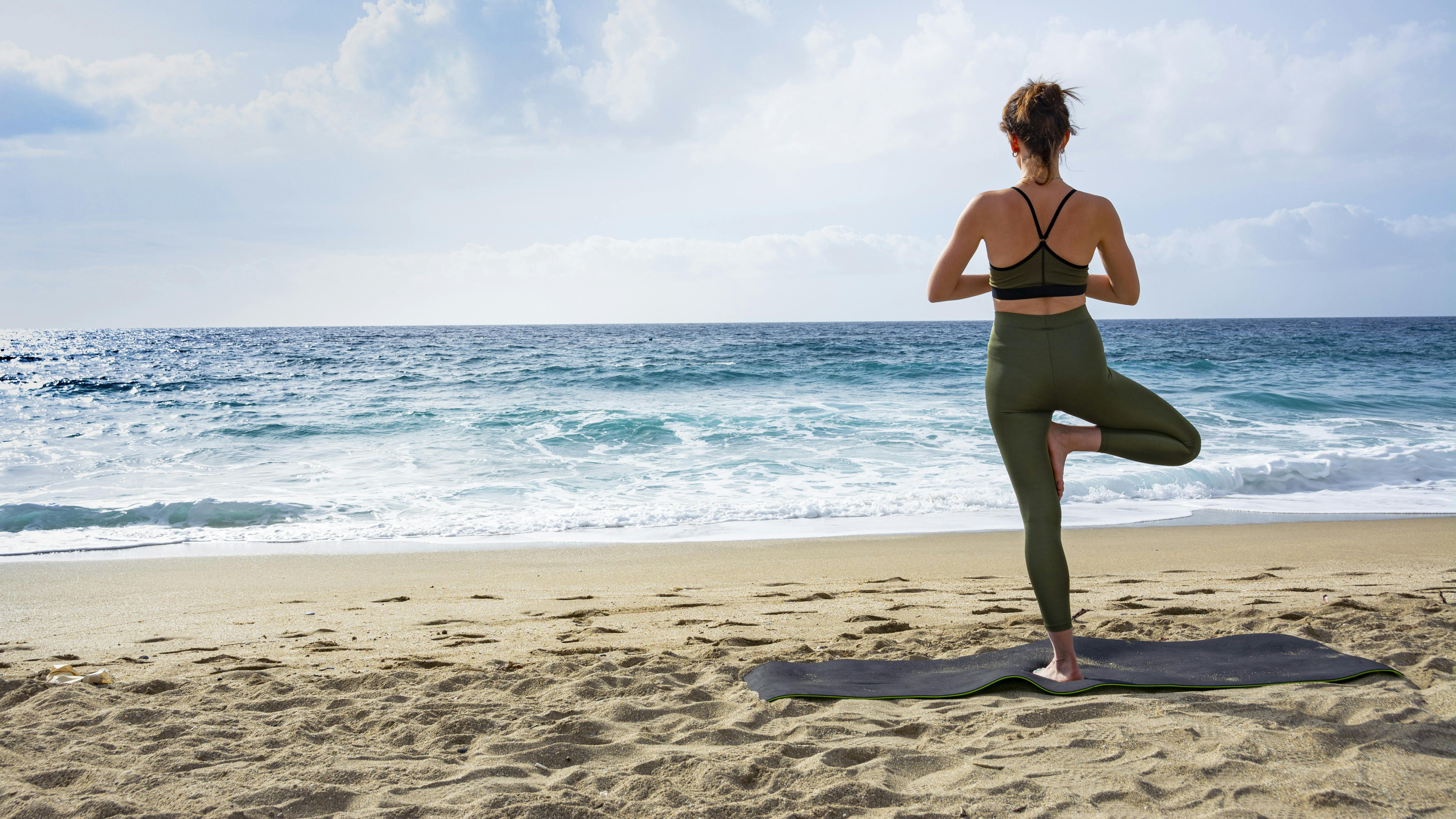 Kvinde, der står på et ben ved strand