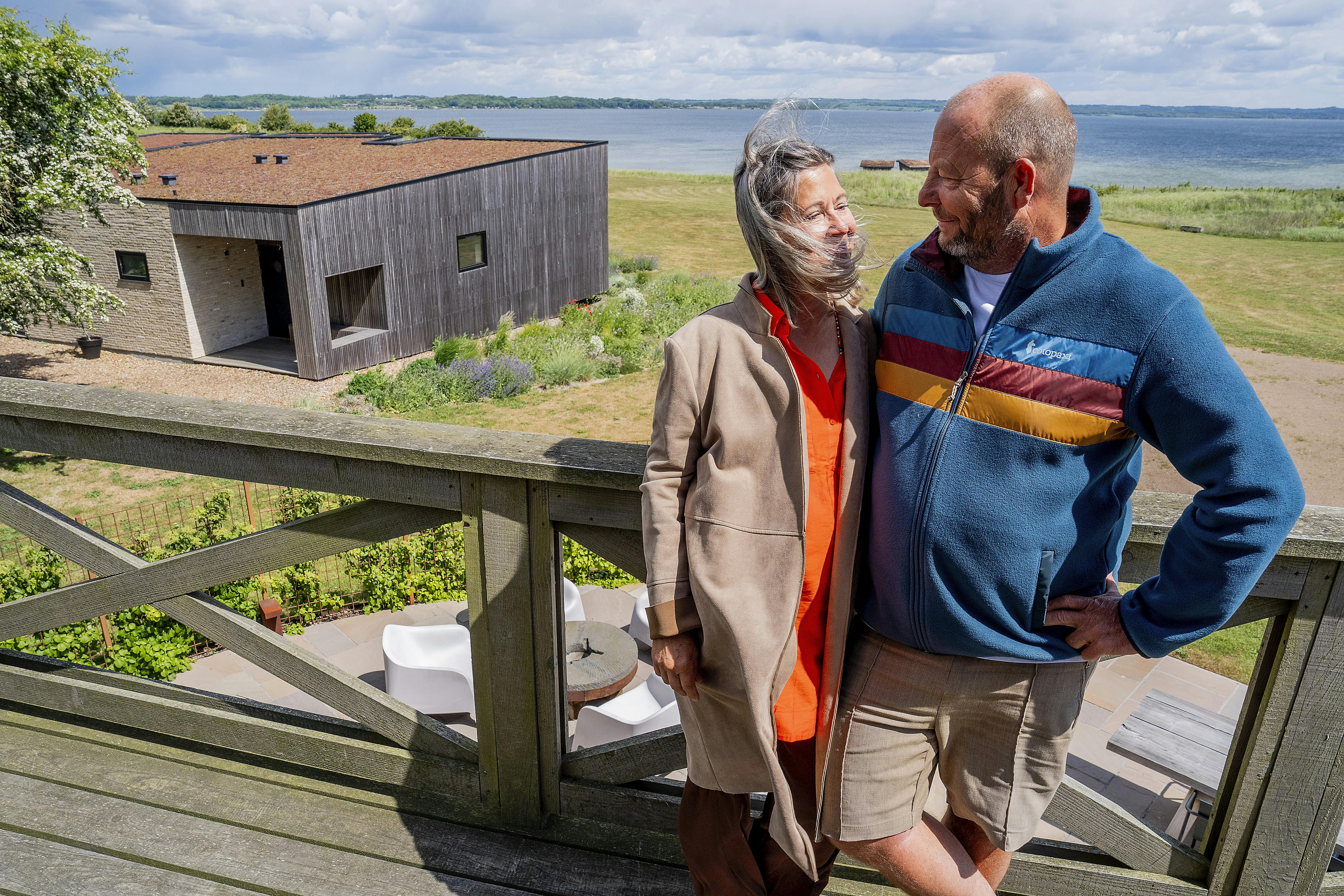 Hanne Plechinger og Stig Nør Larsen fotograferet fra Helnæs Mølle. Bag dem er der udsigt til skøn natur, vand og et par af ægteparrets nye ferieboliger.