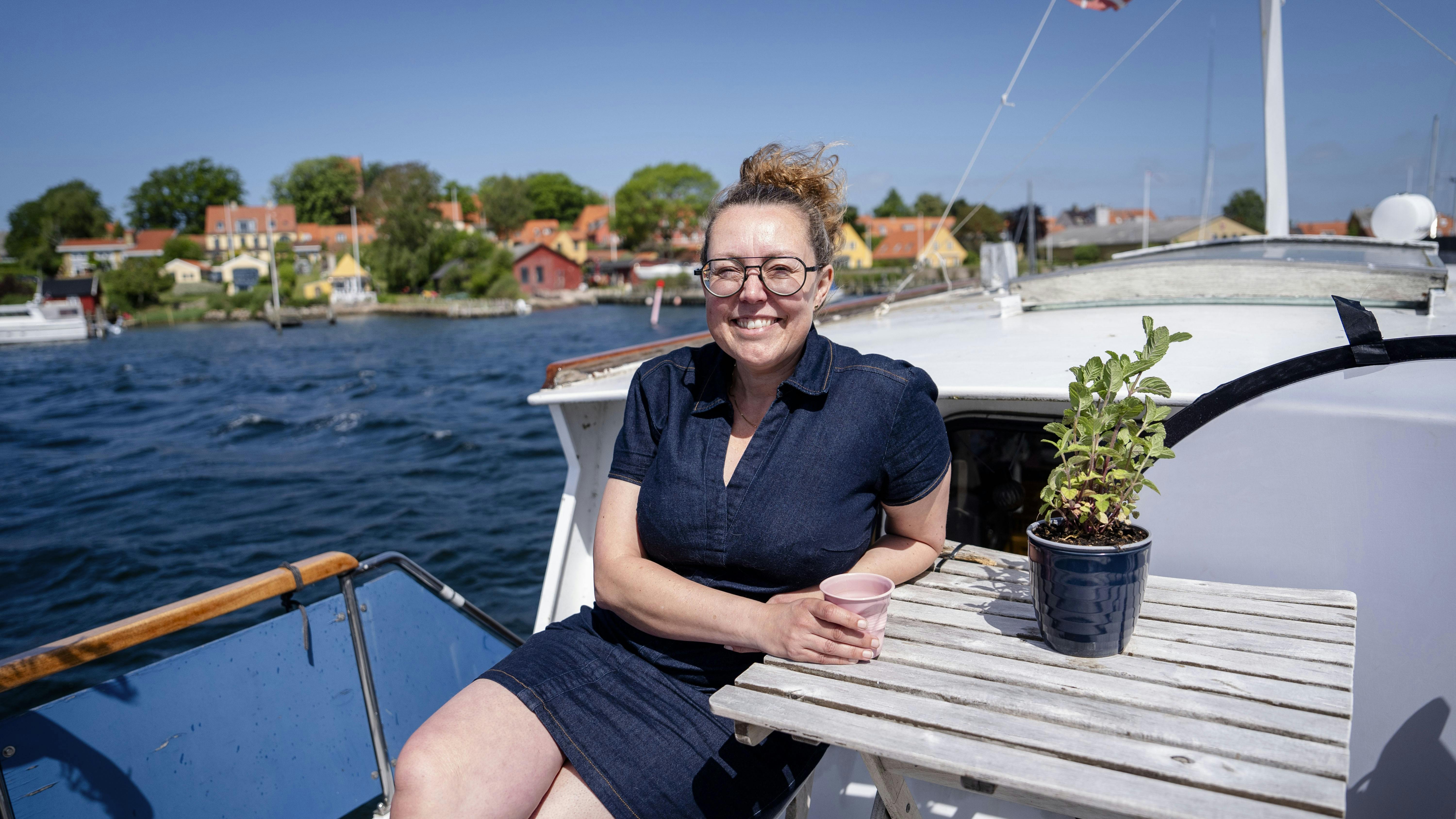 Linda Kristiansen sidder i solen på dækket af sin båd, som hun bor på.