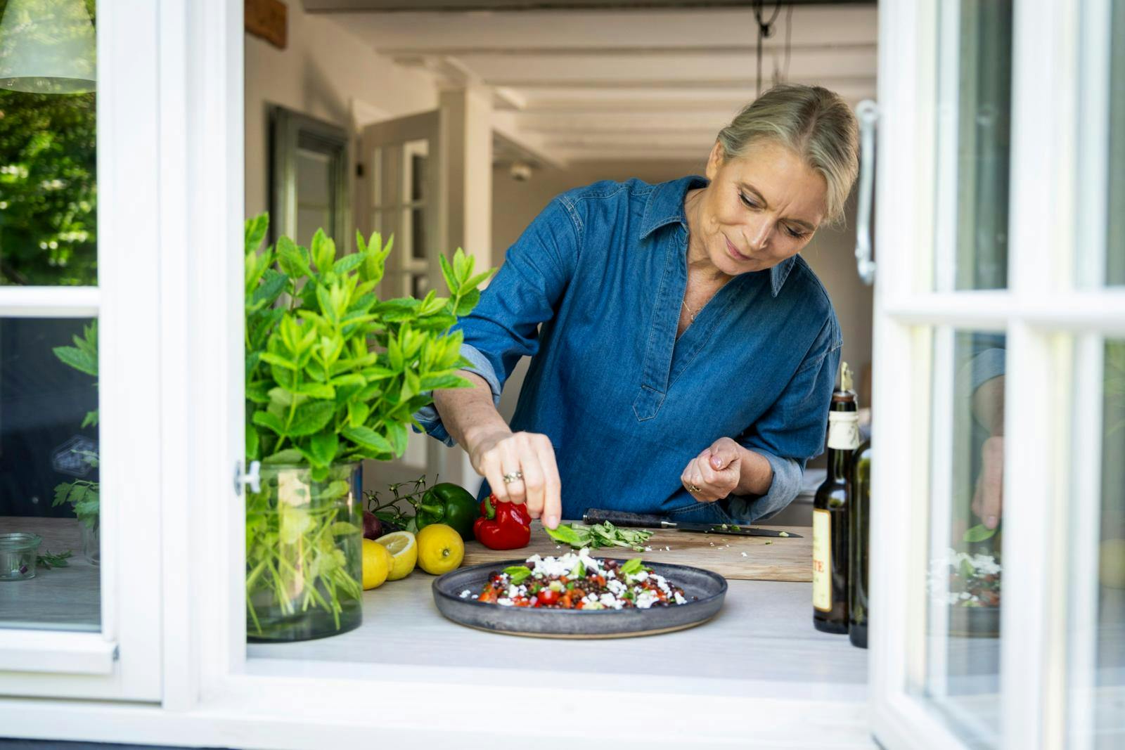 Kvinde, der anretter en salat på en tallerken.