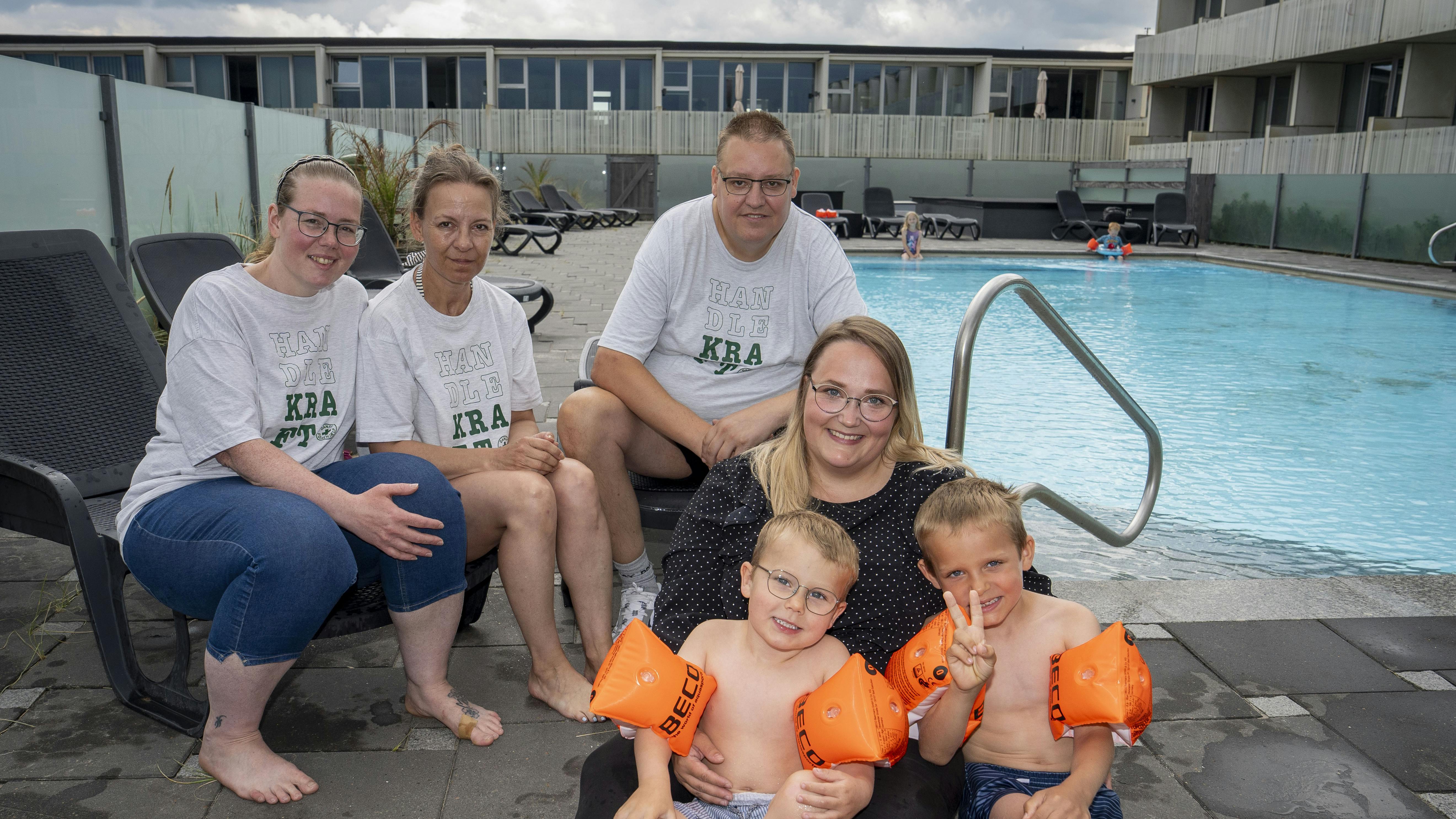 Brian Nielsen sidder ved poolen i Blokhus med sine to hjælpere Anja og Jane i selskab med feriegæsten Katrine Moshave med sønnerne, Theo og Melvin