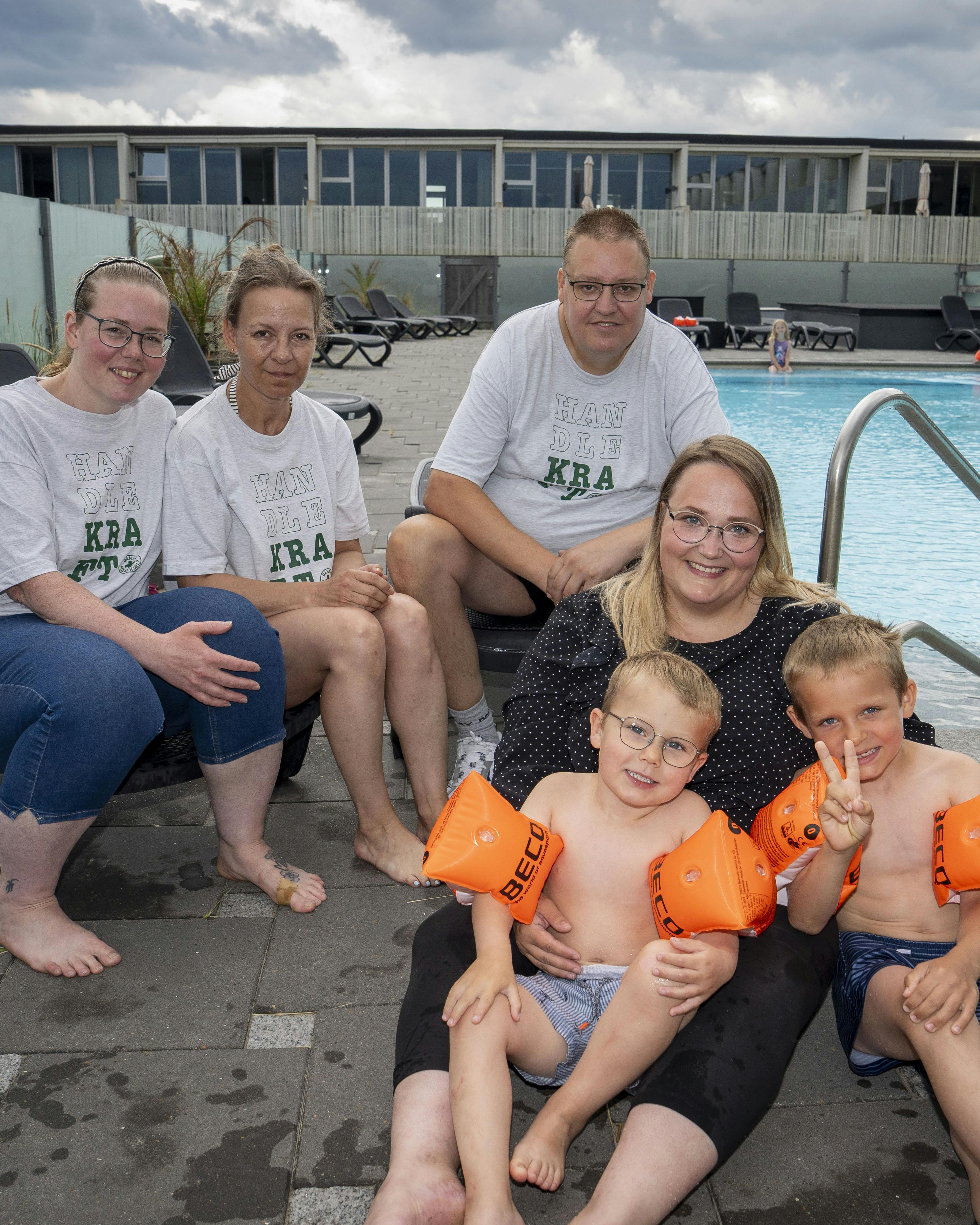Brian Nielsen sidder ved poolen i Blokhus med sine to hjælpere Anja og Jane i selskab med feriegæsten Katrine Moshave med sønnerne, Theo og Melvin