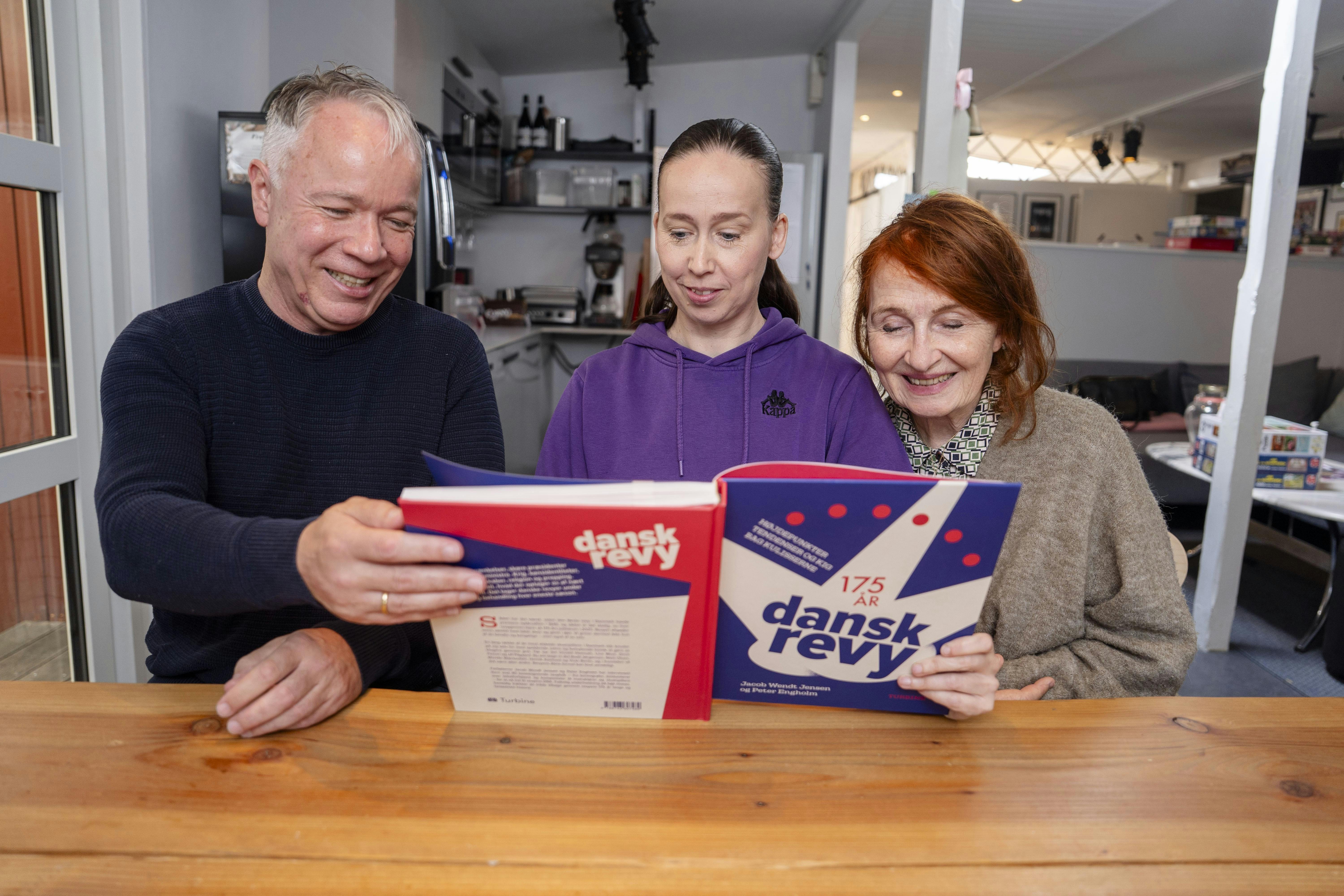 Bodil Jørgensen, Merete Mærkedahl og Peter Engholm kigger i bogen "Dansk revy 175 år", som sidstnævnte er medforfatter til.