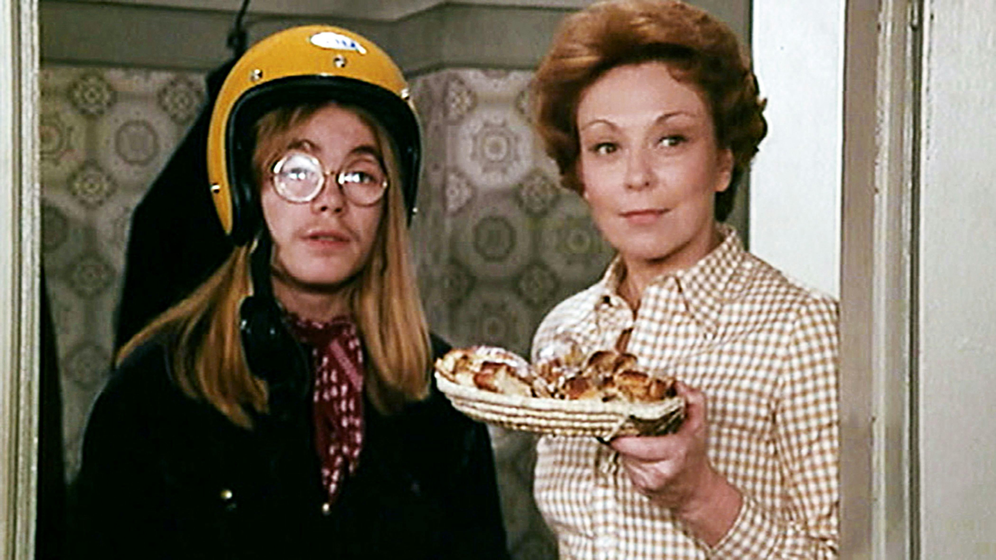 Helle Virkner med en tallerken i hånden. Ved siden af ses en stor dreng med styrthjelm på.