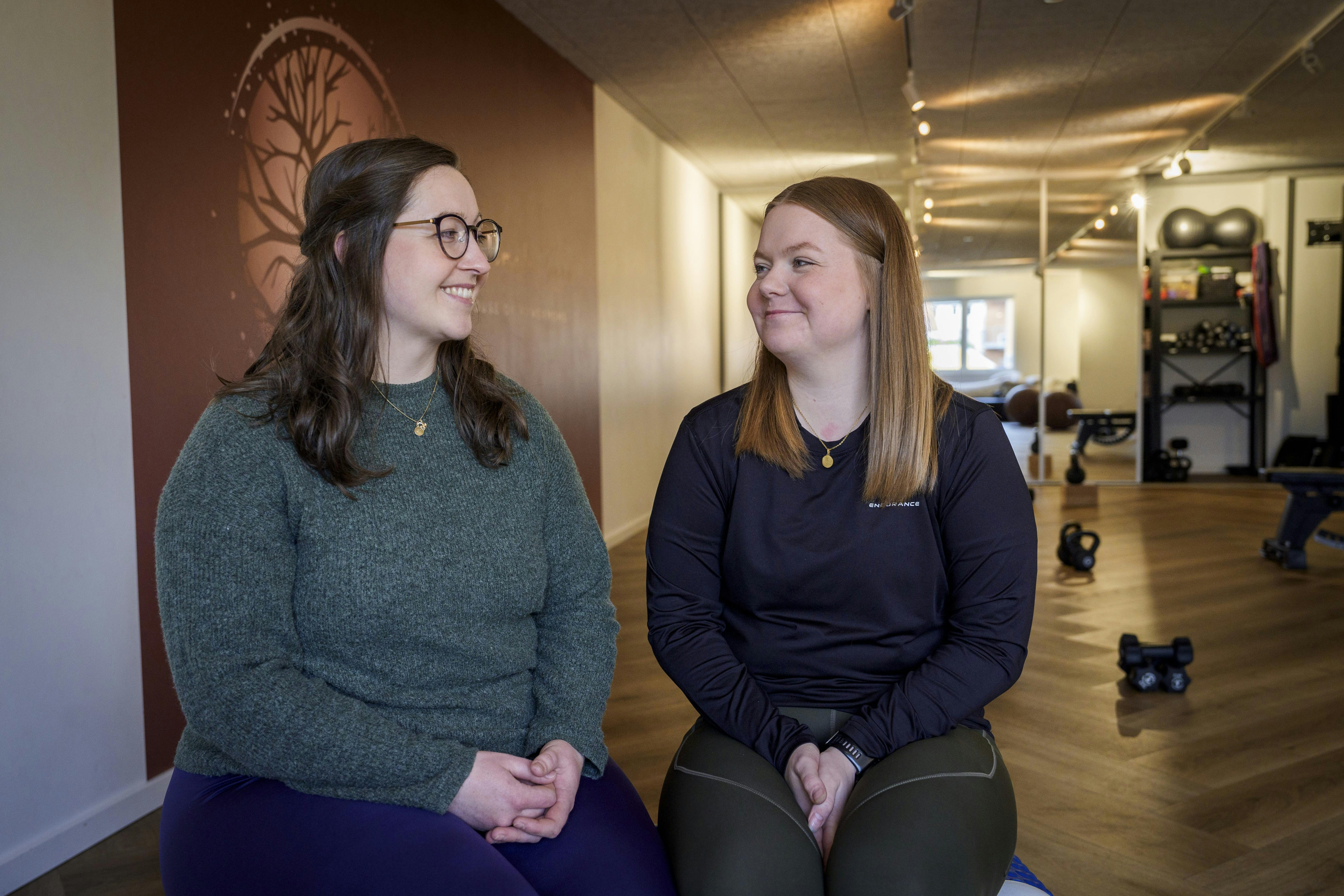 Pernille og Majken sidder i træningslokalet og kigger på hinanden med et smil