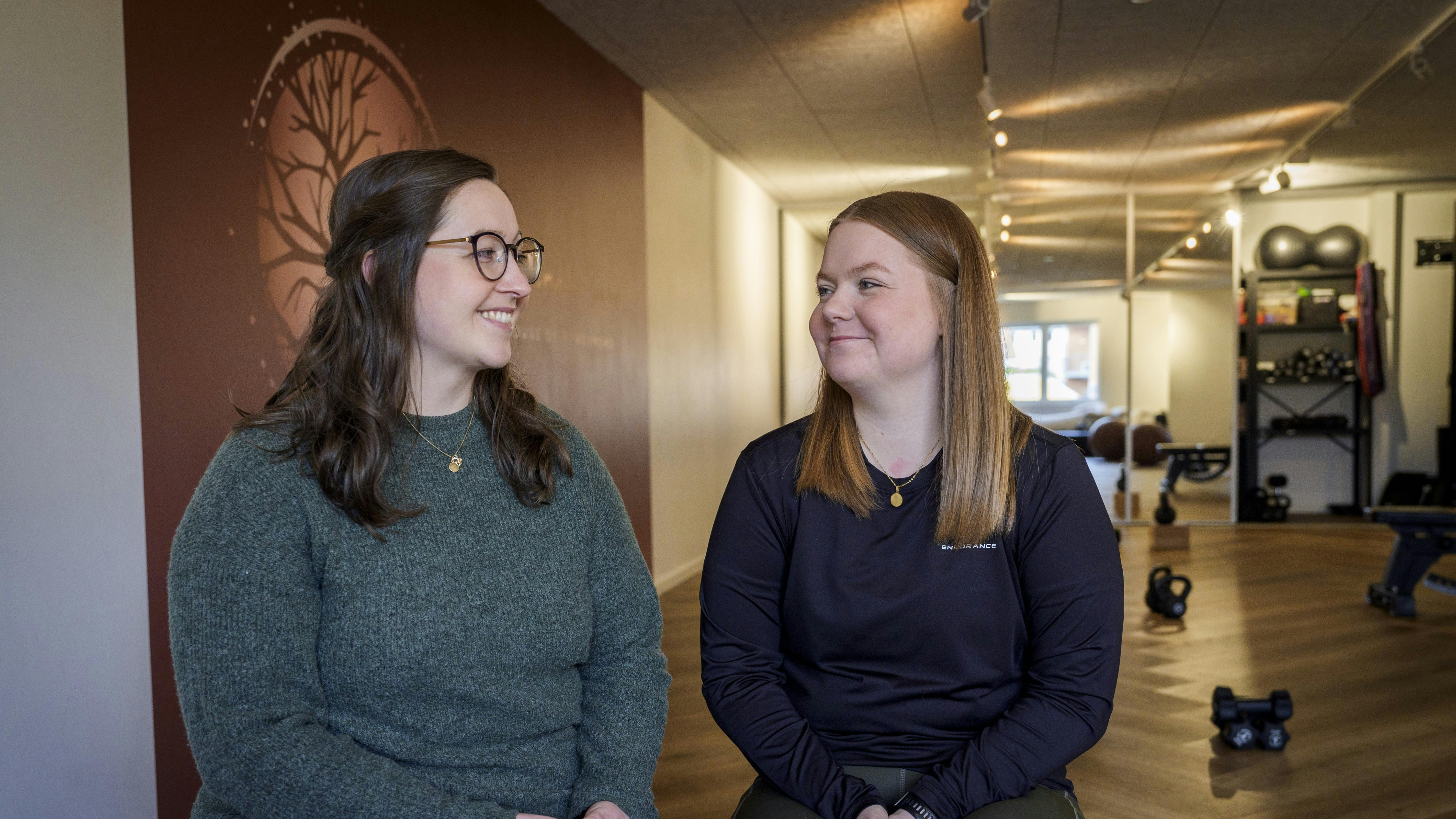Pernille og Majken sidder i træningslokalet og kigger på hinanden med et smil