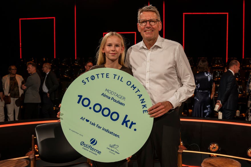 Alma og hendes far står med et skilt