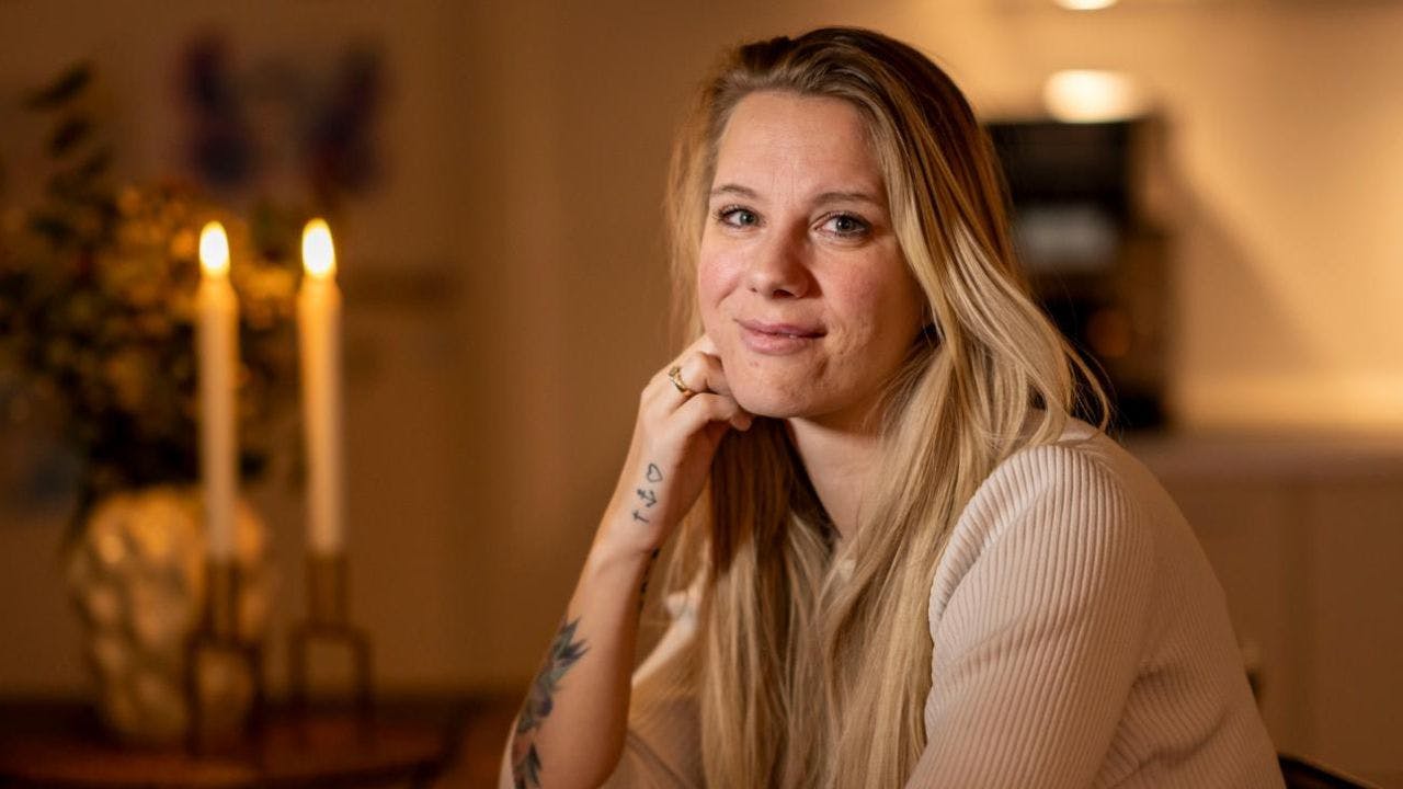 Anja sidder i stue med stearinlys i baggrund