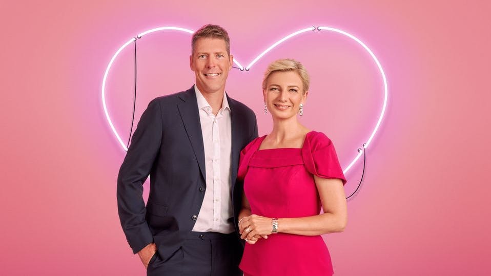 Louise Wolff og Steen Langeberg står foran et lyserøde lysende neonhjerte