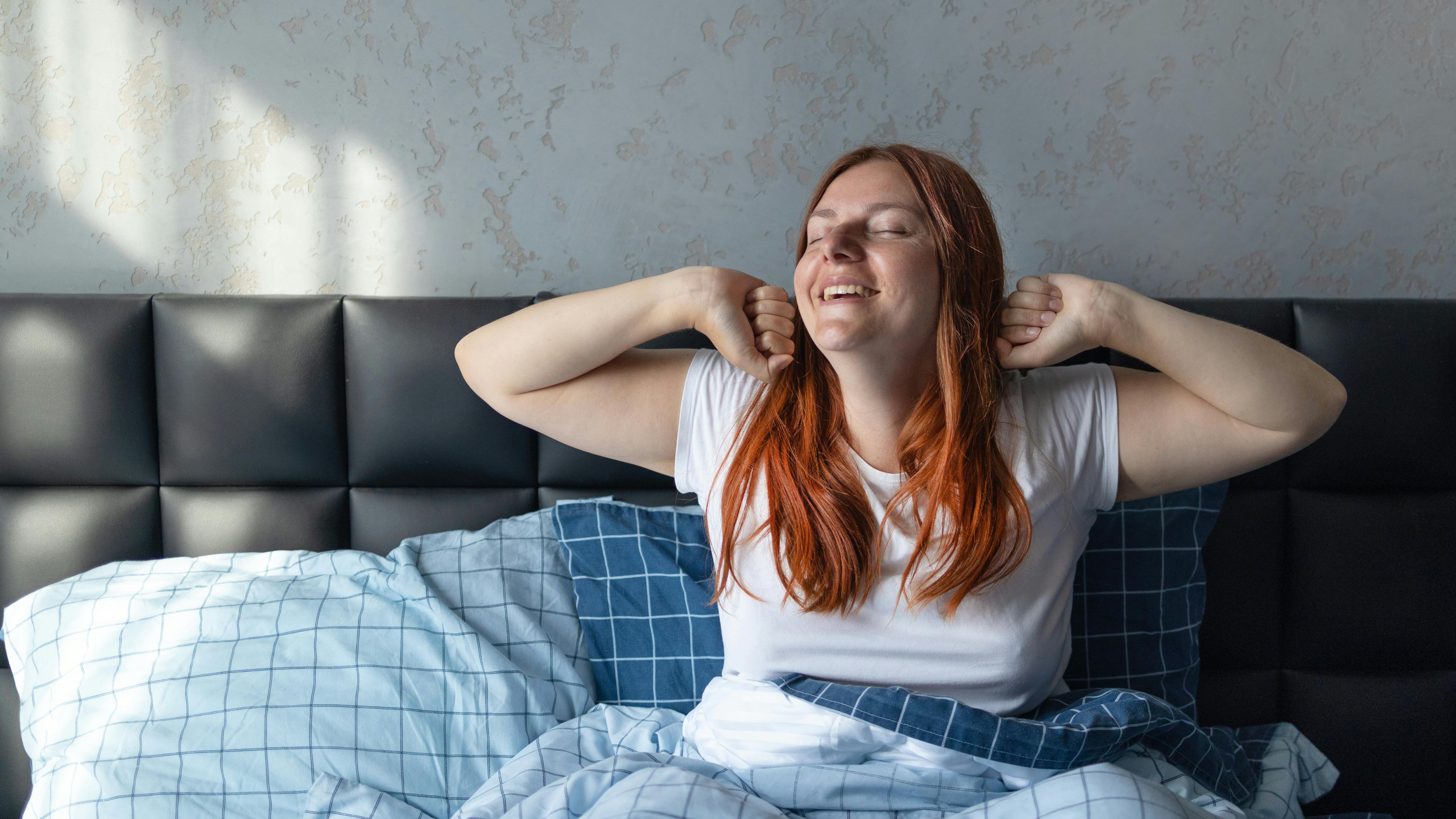 Kvinde strækker sig i sengen