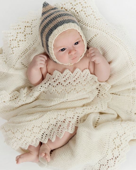 Rundt babytæppe svøbt om baby med hue