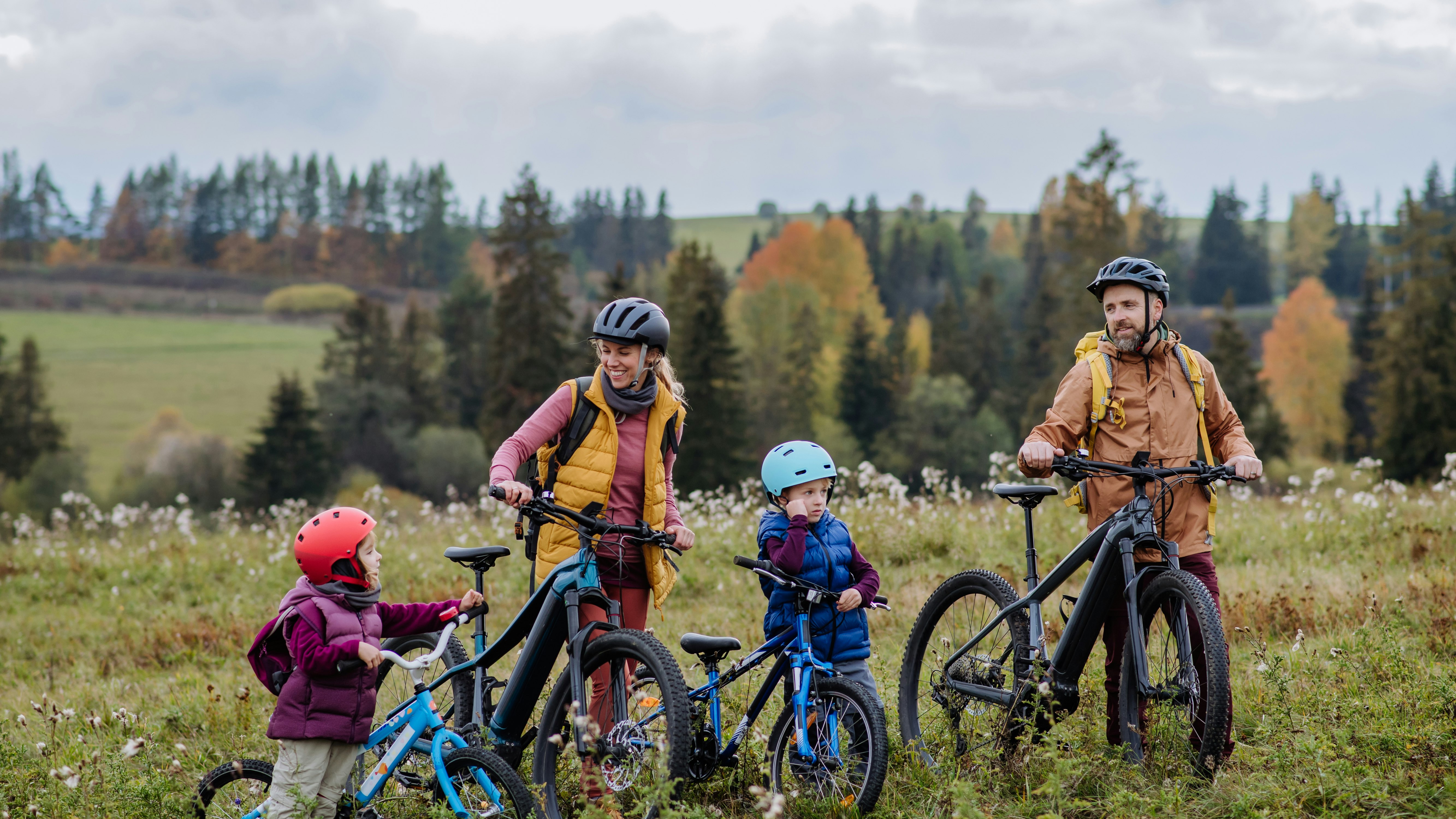 Ung familie med børn på cykeltur i efterårslandskabet.