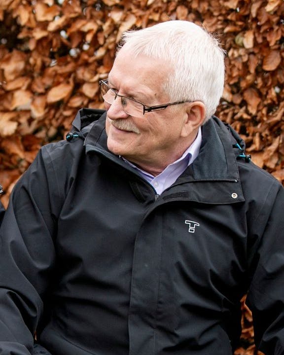 Et ældre ægtepar kigger smilende på hinanden på en bænk