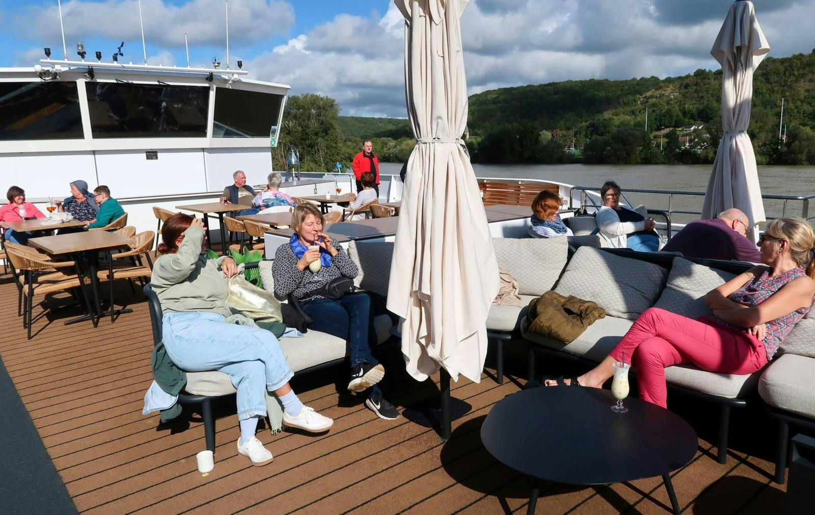 Et soldæk på et skib, hvor folk ligger i solstole og nyder solen. 