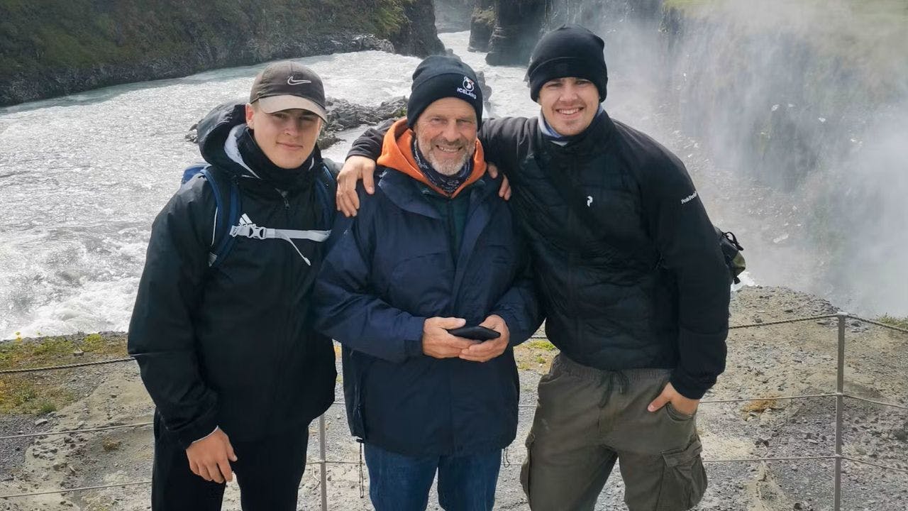 Far står med sine to sønner på hver side i islandsk landskab