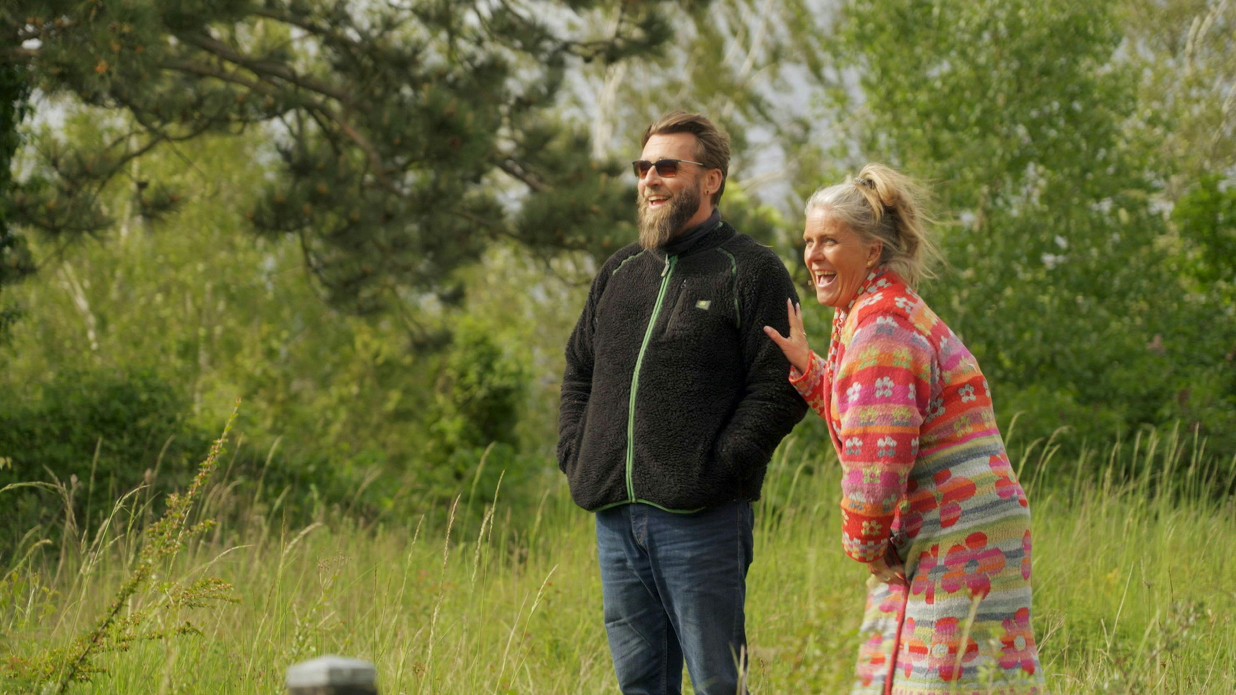 Et par der står i naturen og smiler.