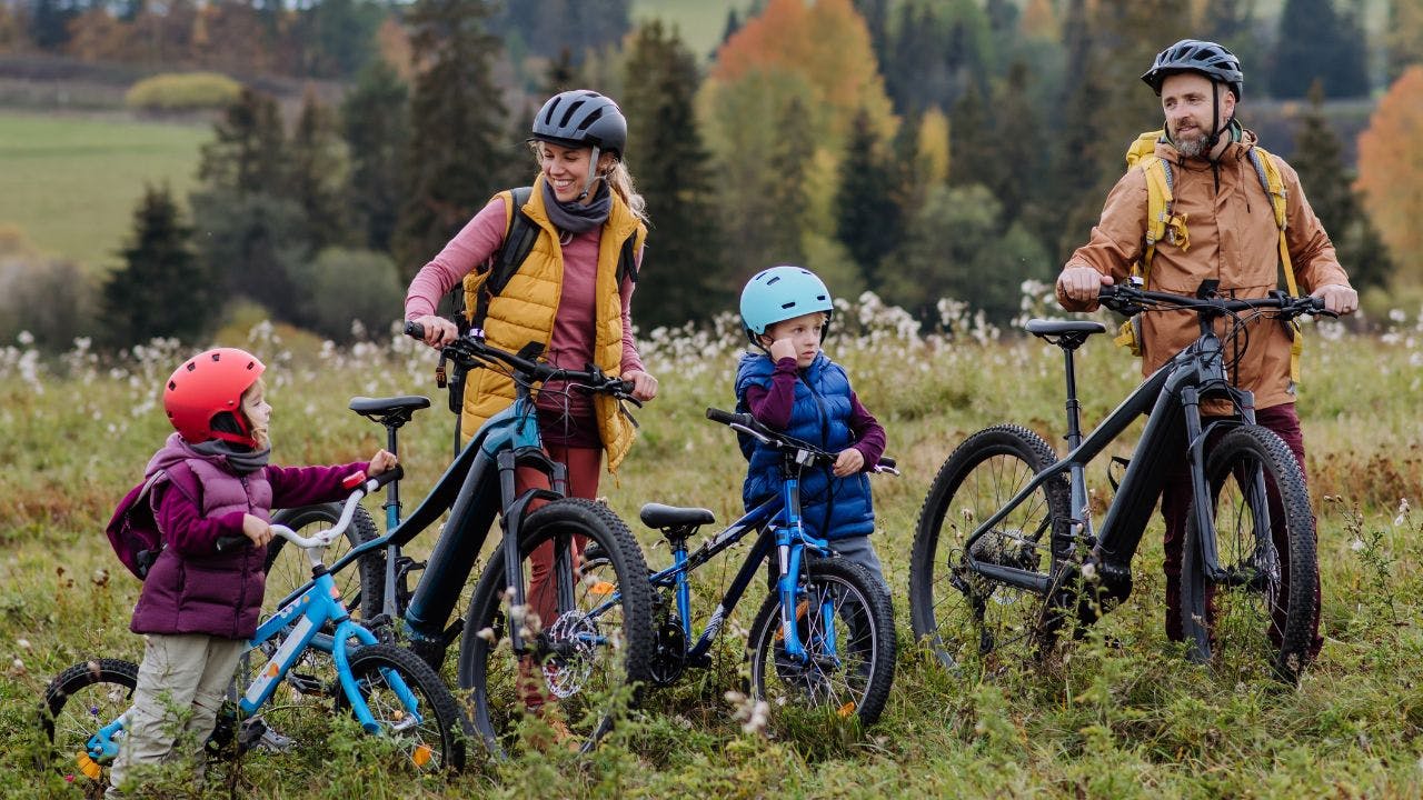 Ung familie med børn på cykeltur i efterårslandskabet.