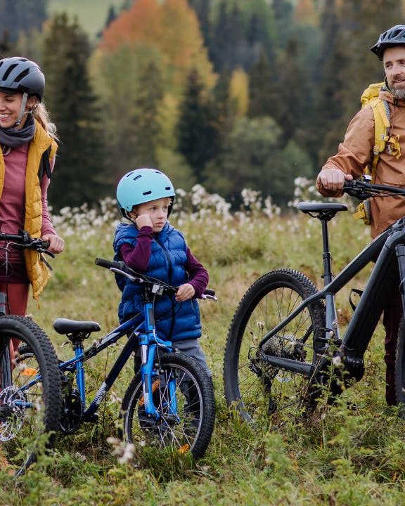 Ung familie med børn på cykeltur i efterårslandskabet.
