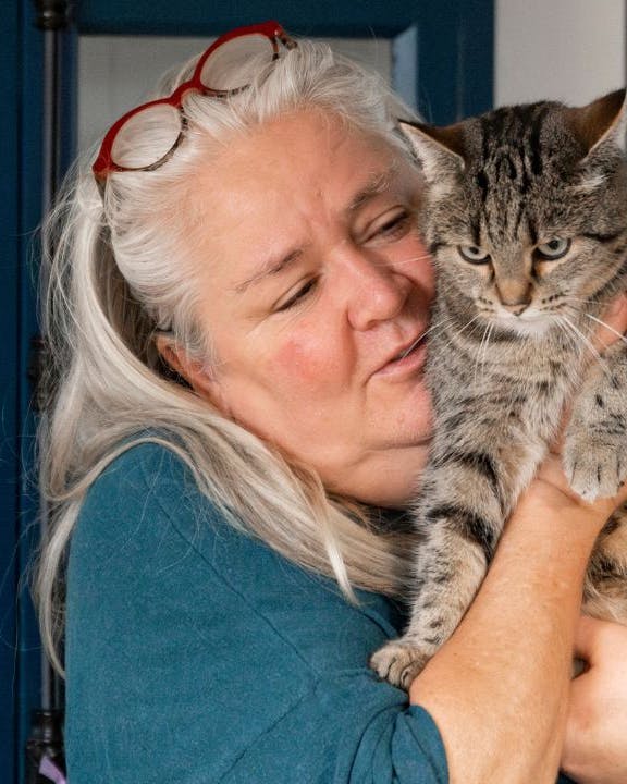 Kvinde krammer en grå kat