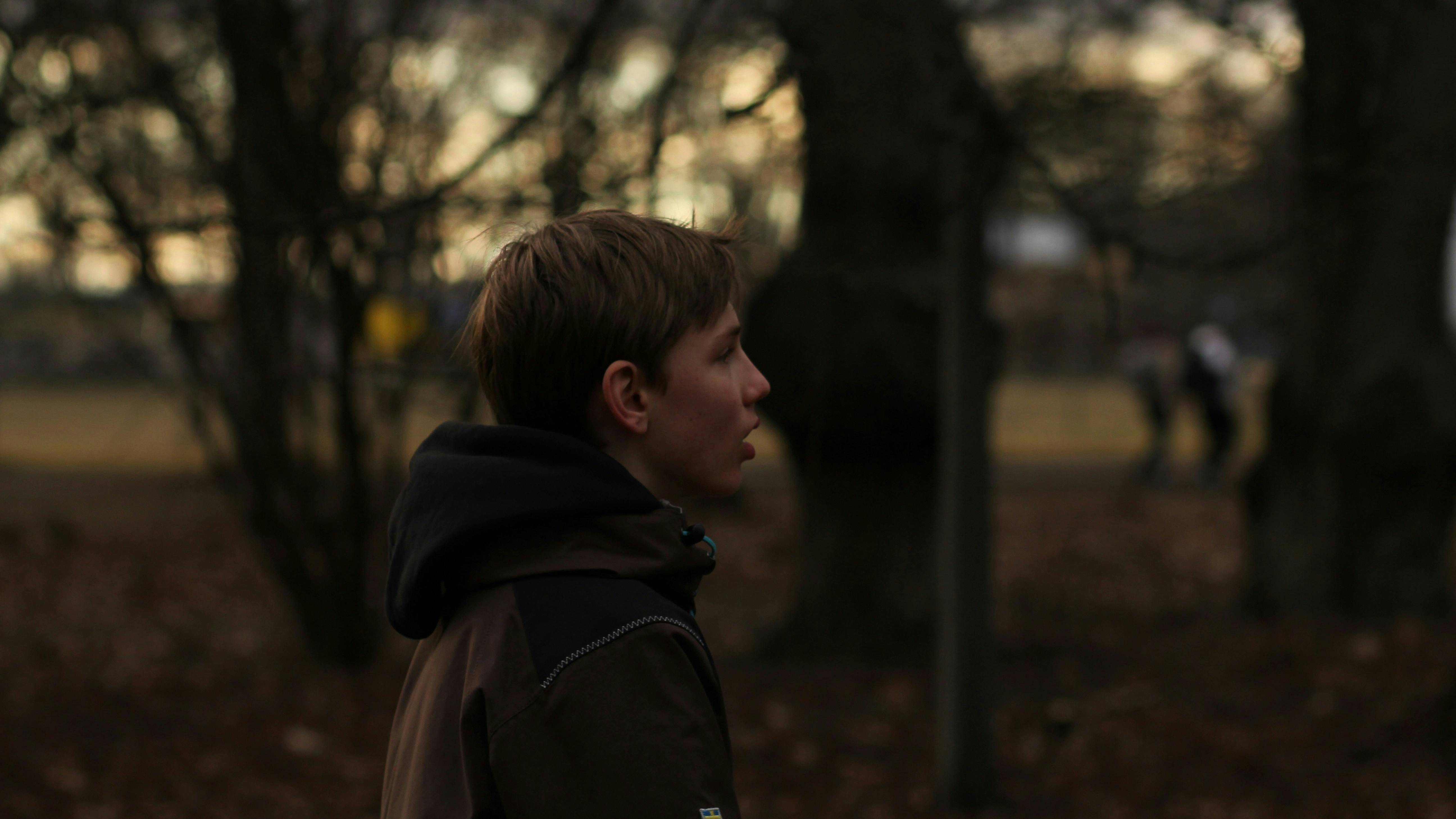 En dreng, der går i en skov i tusmørke