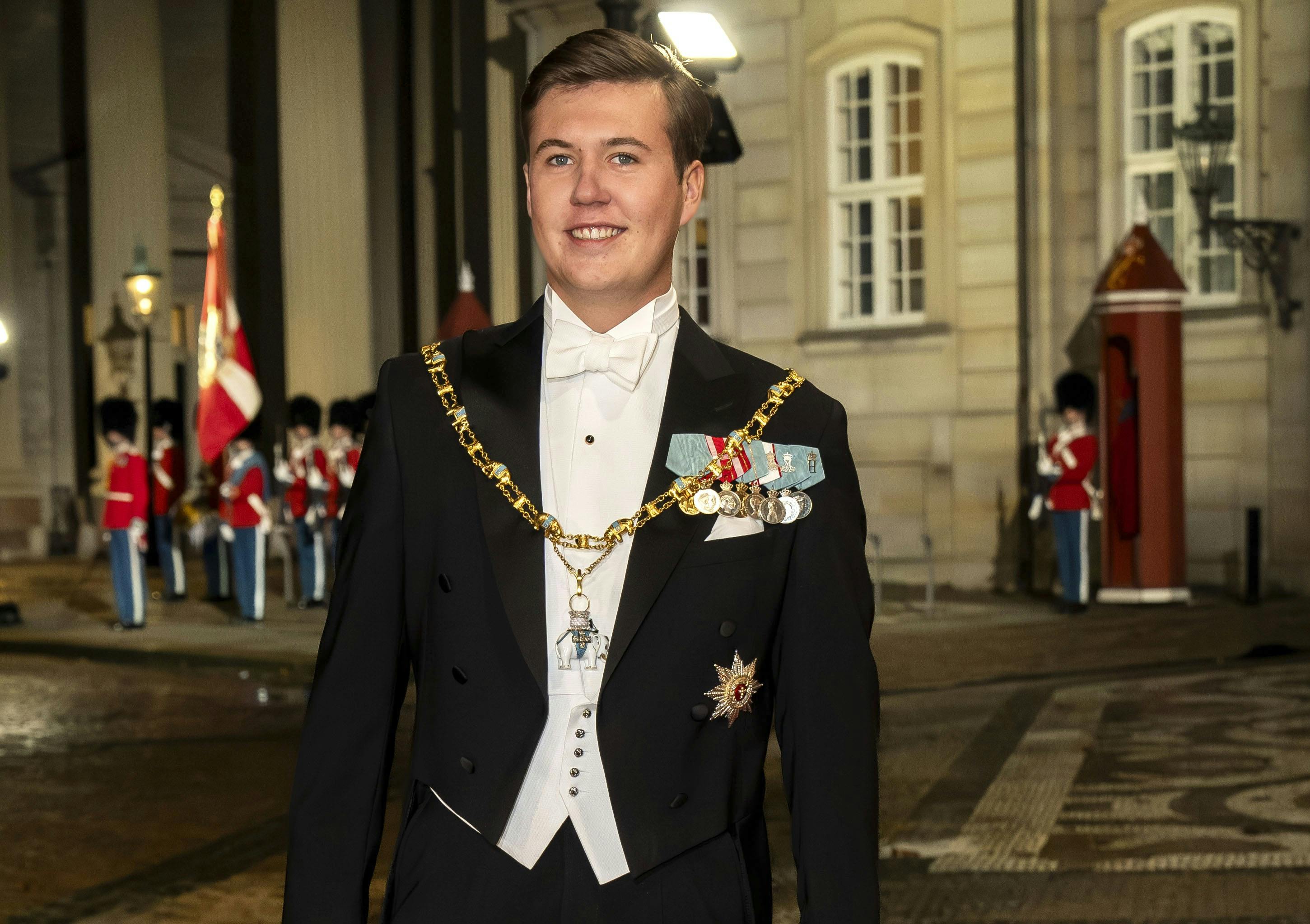 Kronprins Christian i gallauniform foran Amalienborg Slot med garderne i baggrunden.