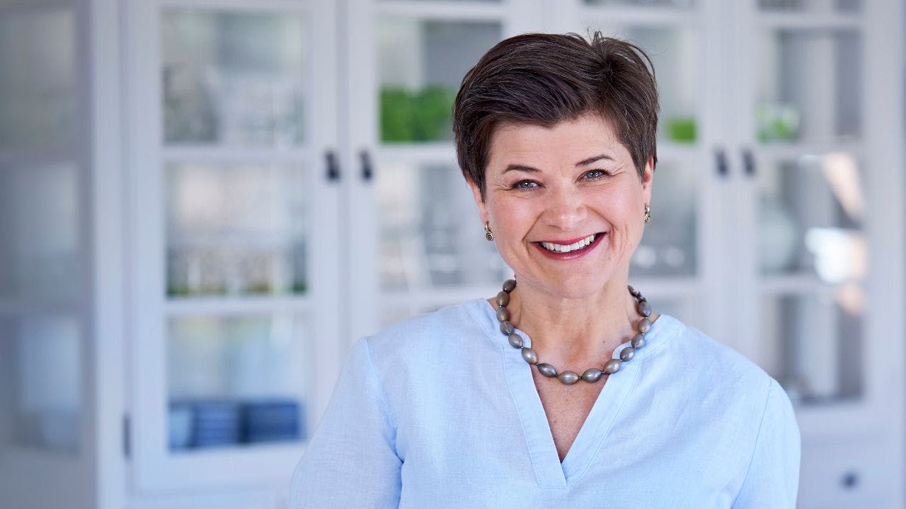 Voksen kvinde smiler i blå skjorte