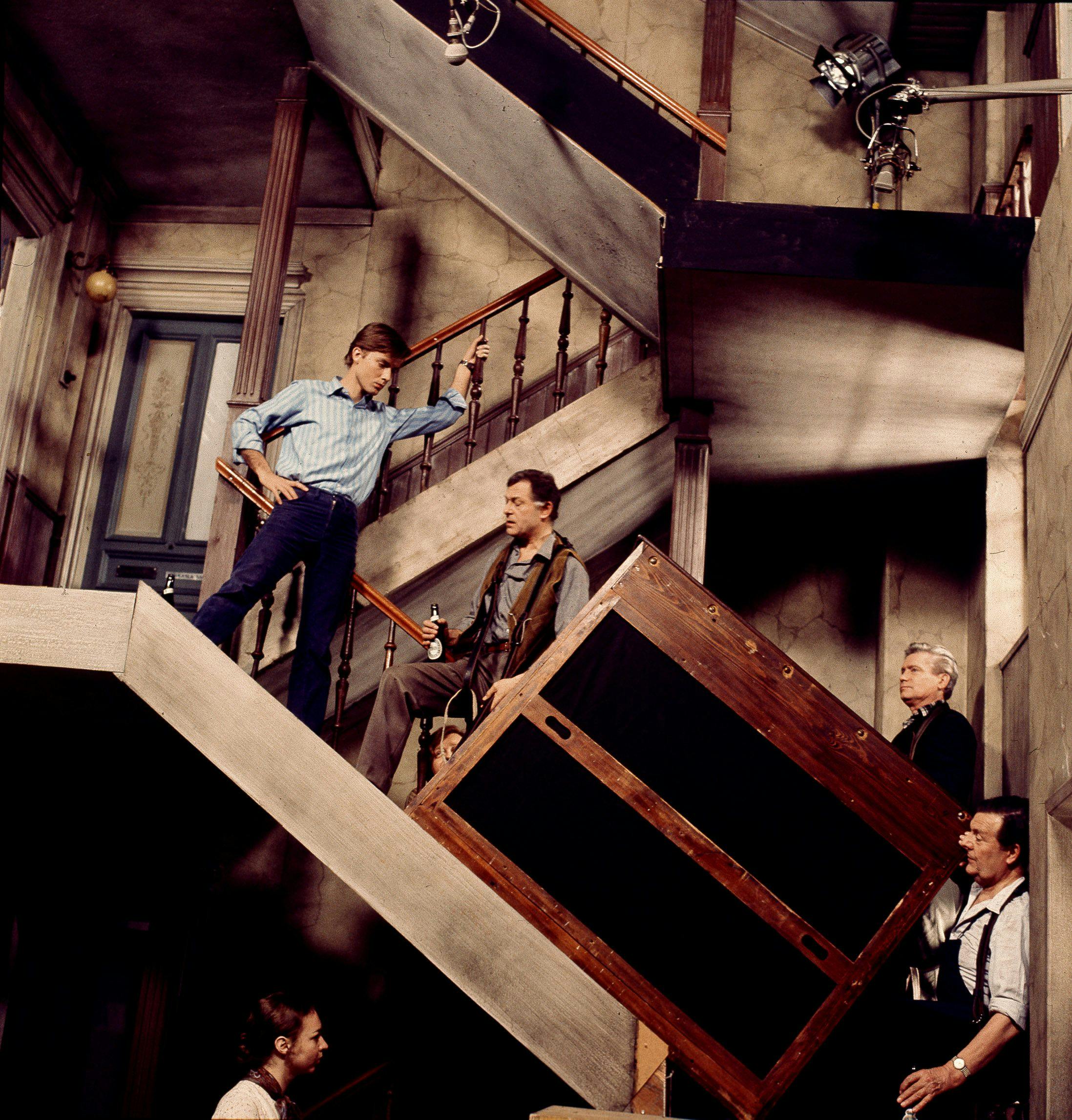 Fire mænd, der bærer et tungt møbel op ad en trappe.