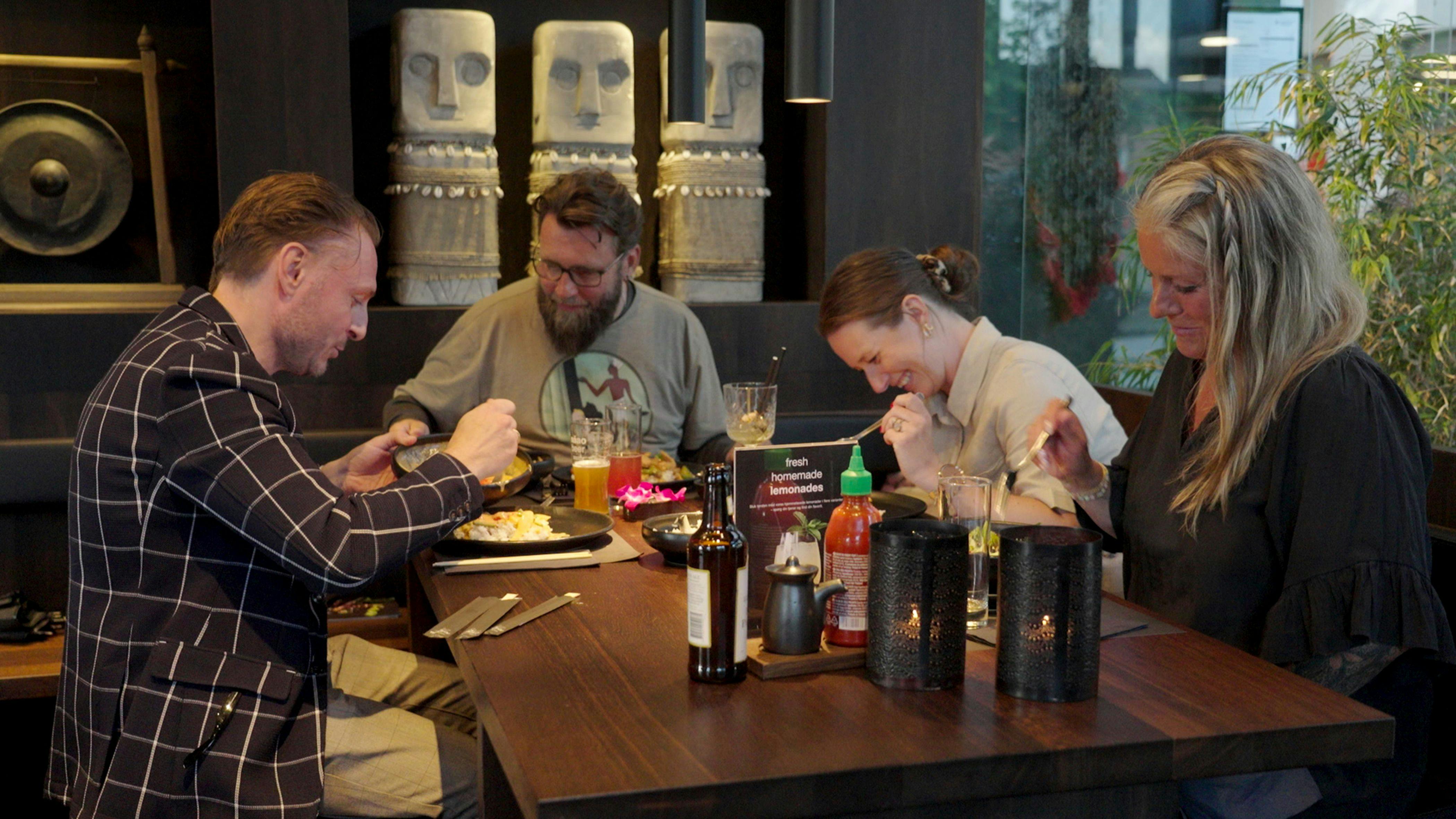 To mænd og to kvinder, der sidder ved et brunch-bord og griner. 