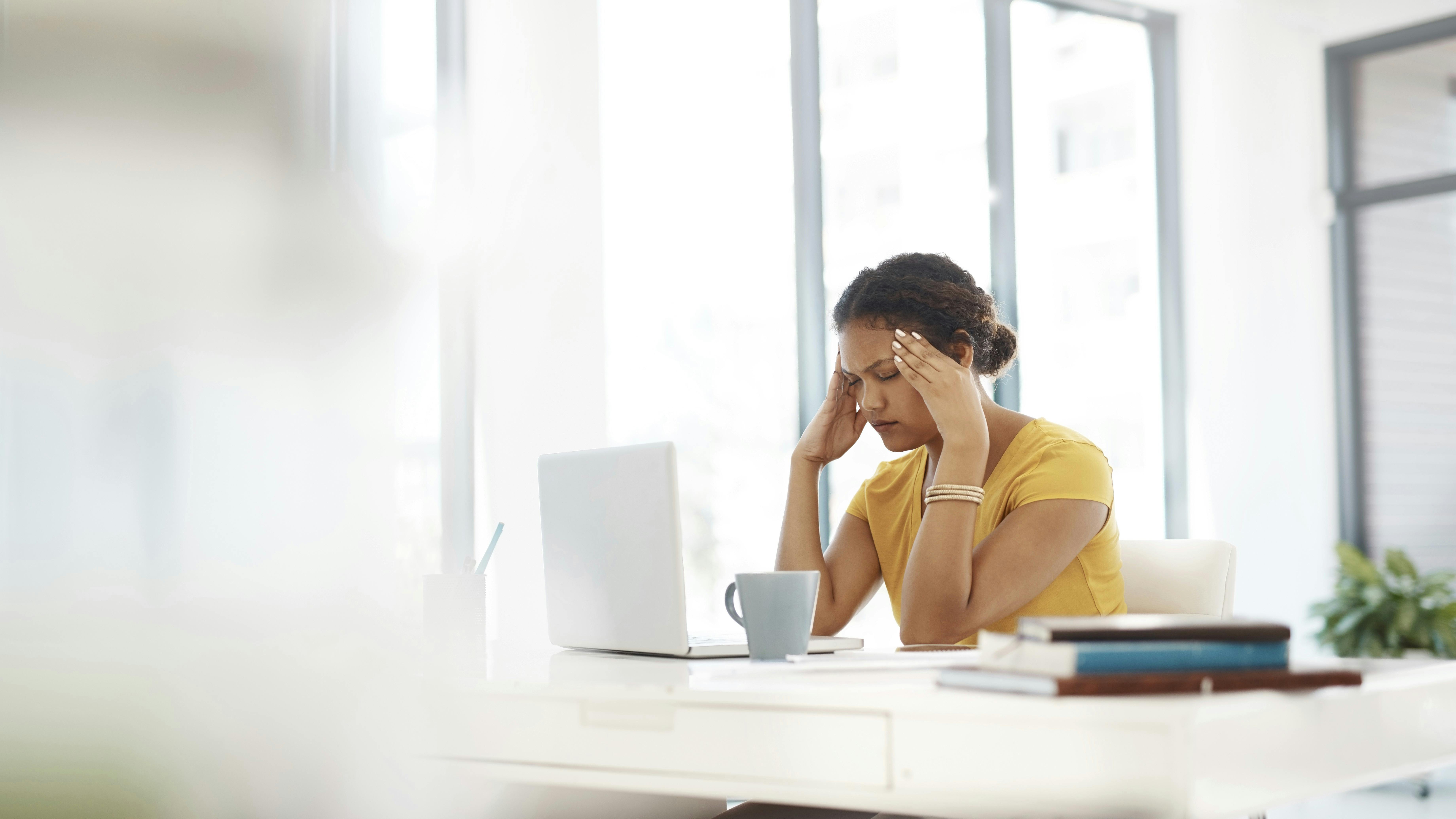 Foto af kvinde der sidder træt ved en pc.