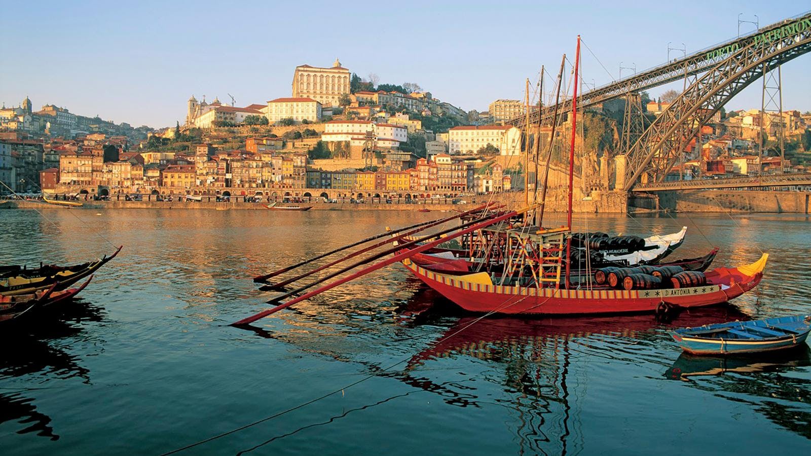 En gammeldags sejlbåd, der ligger i vandet tæt på en kyst i Portugal