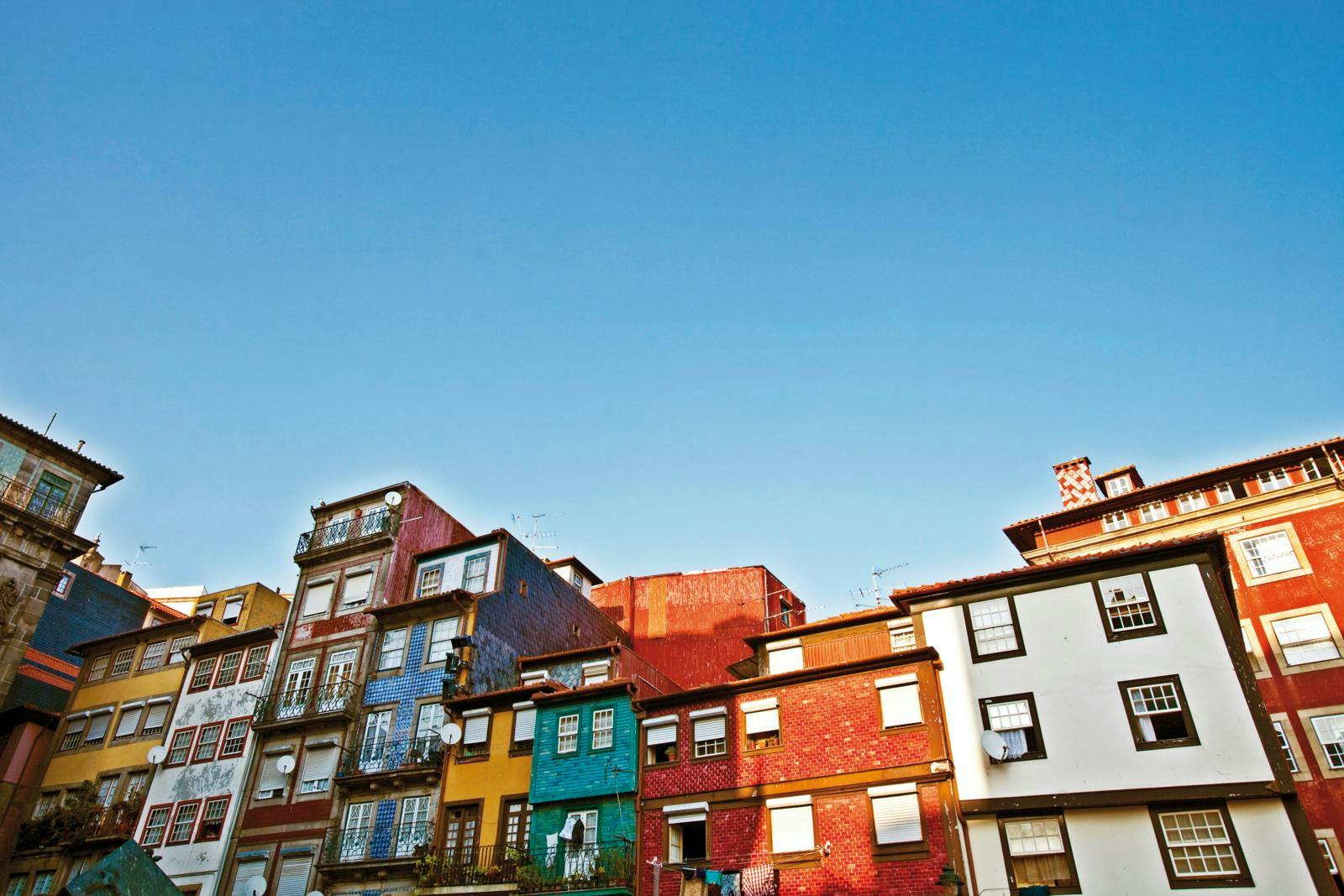En række farverige huse ved siden af hinanden med en blå himmel over.