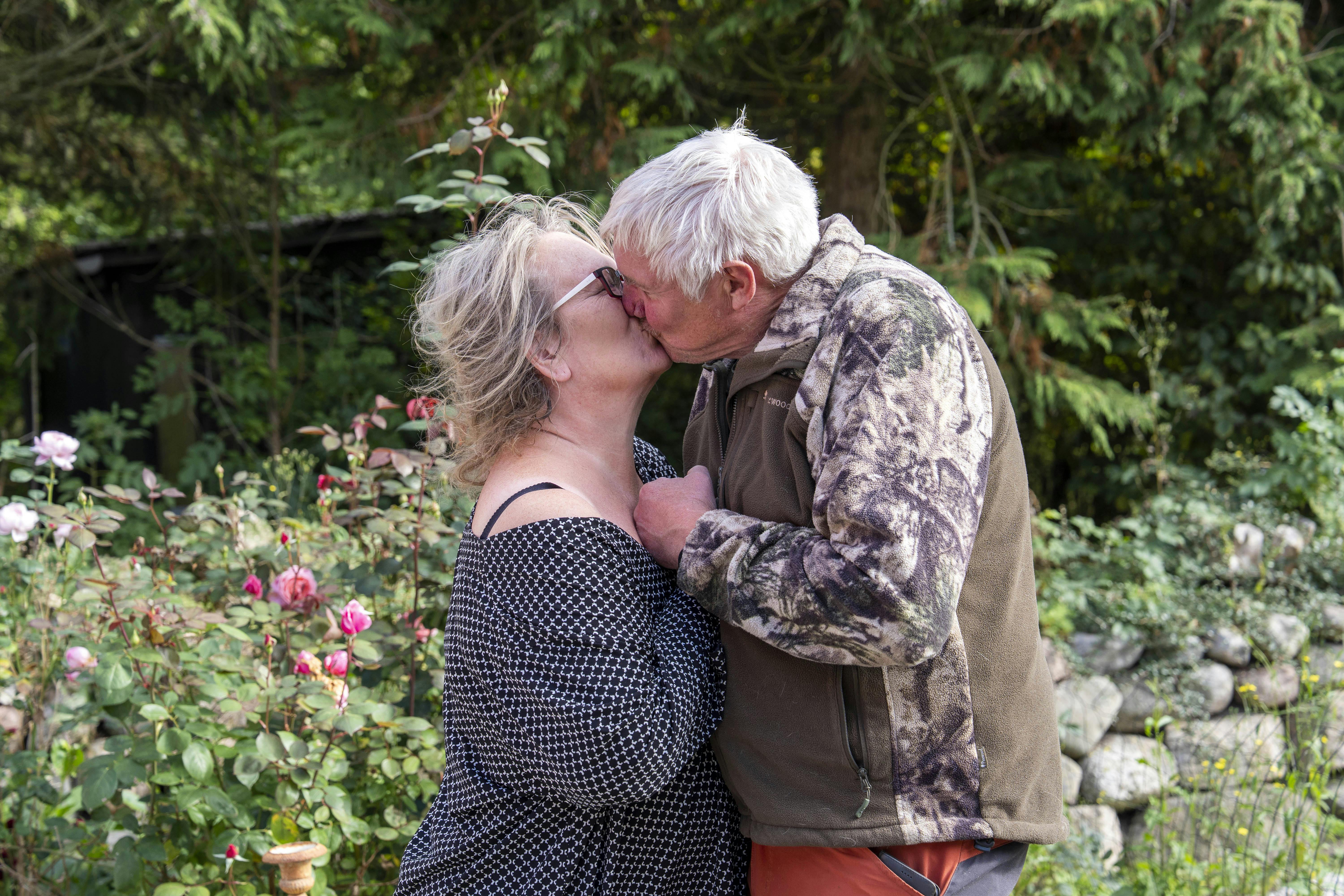Ældre kærestepar kysser i en have omgivet af grønt