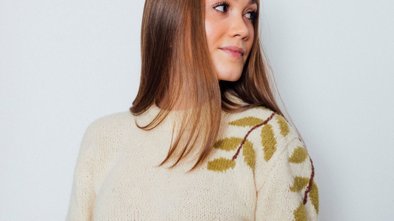 Kvinde med sweater med blade kigger over skulderen