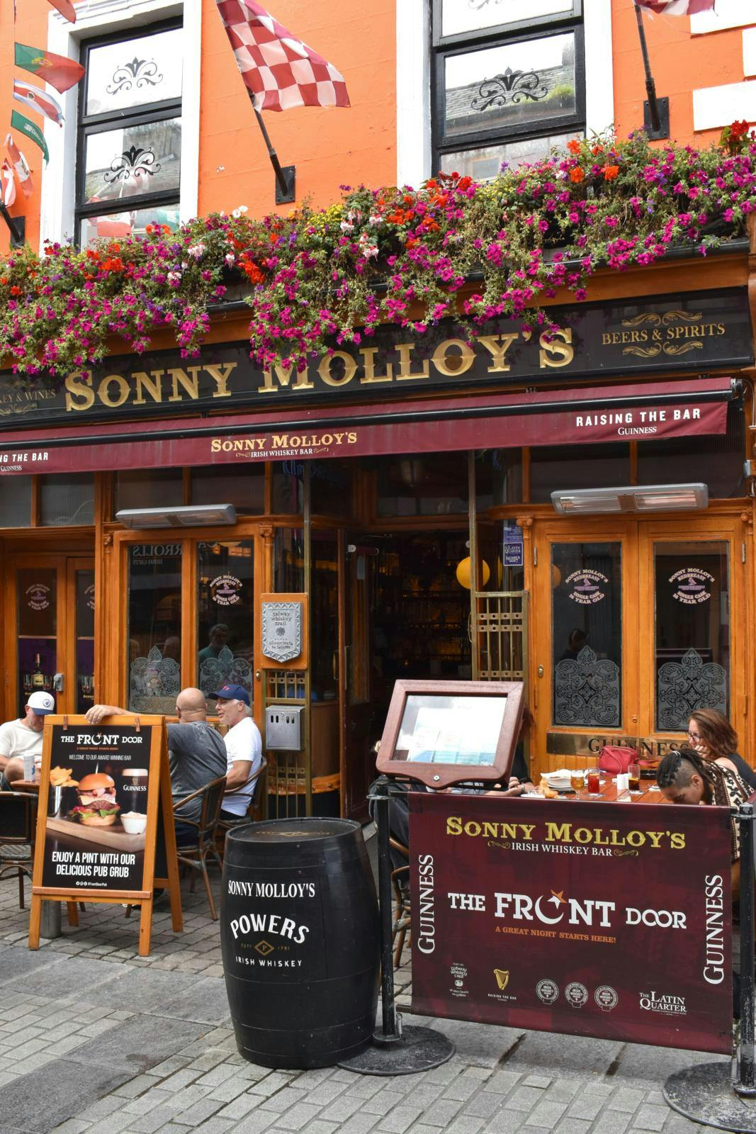 En pub-facade i mørkerøde farver og med blomster foroven.