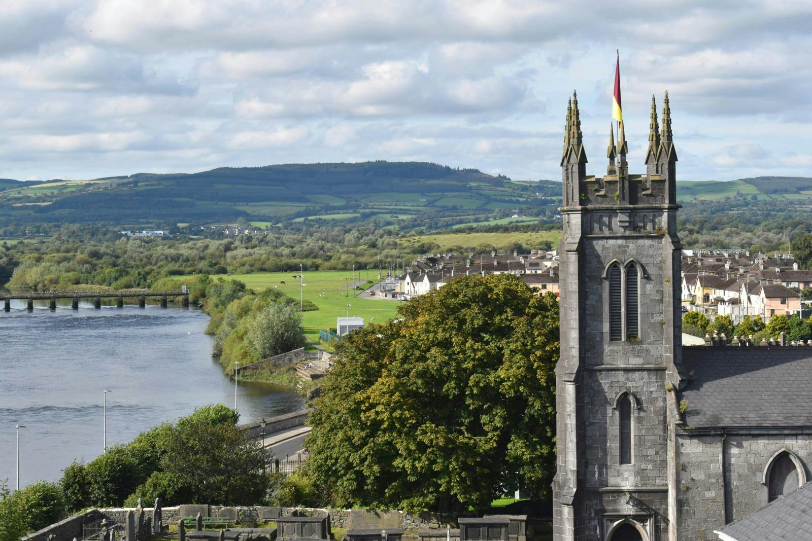 Et landskab bestående af en stor sø, grønne marker og træer samt en middelalderborg.