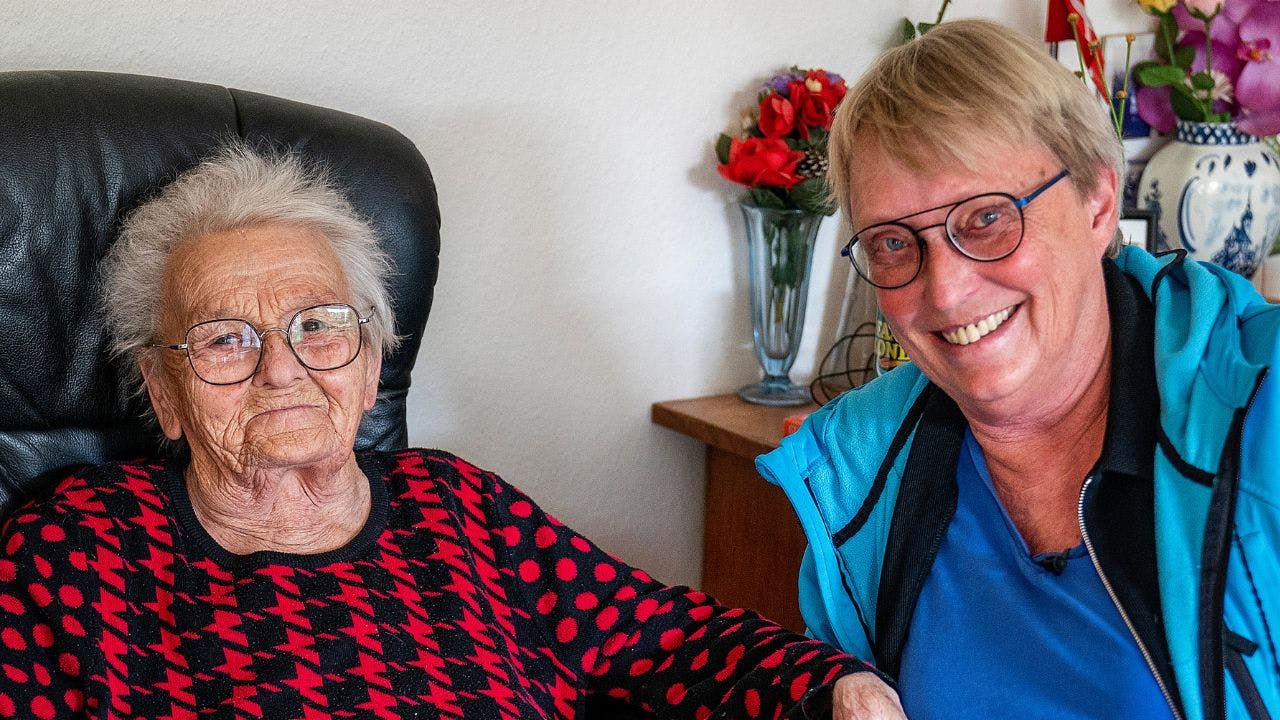 To ældre kvinder sidder ved siden af hinanden og smiler