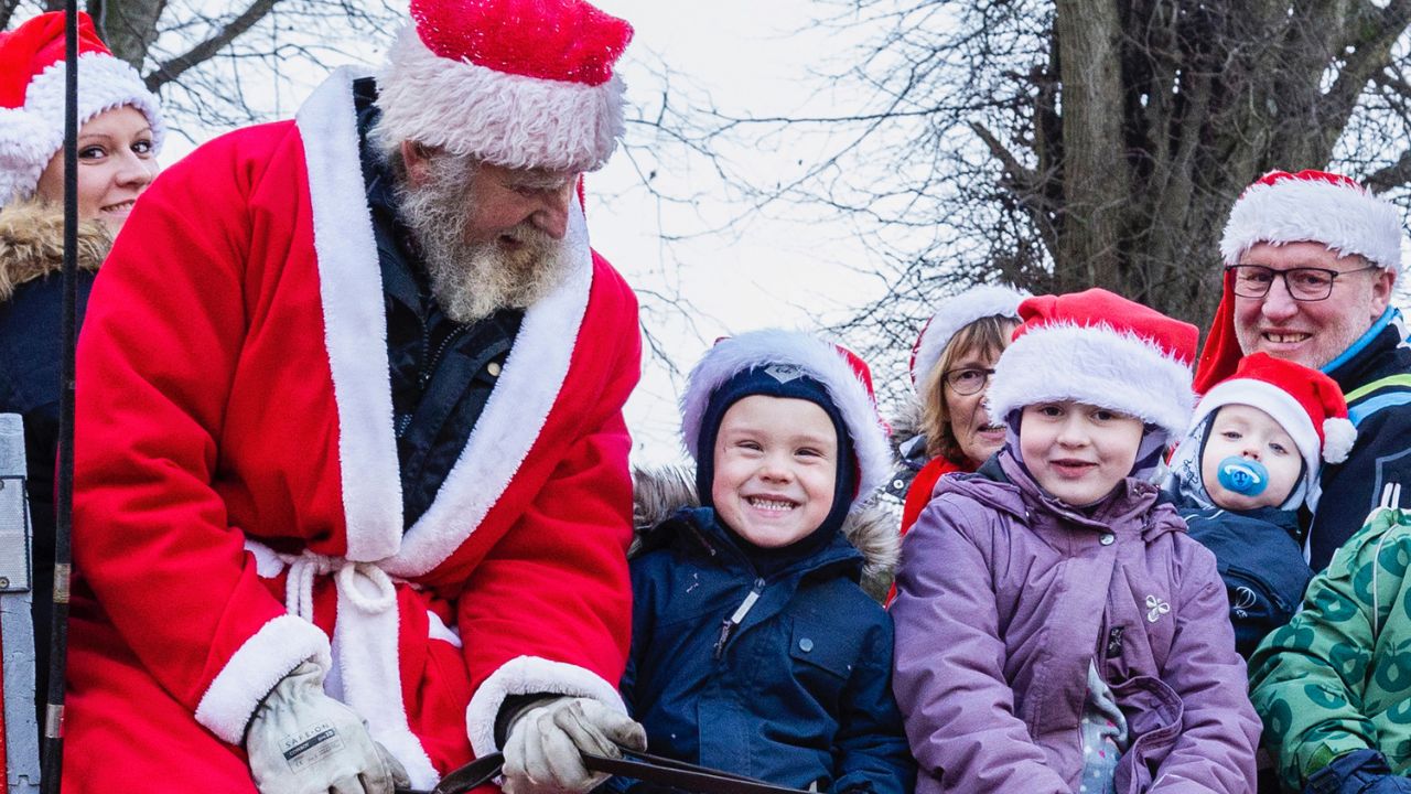 Børn sidder i hestevogn med en julemand og smiler