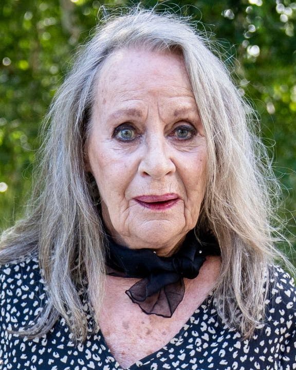 Ældre kvinde står foran grønne træer